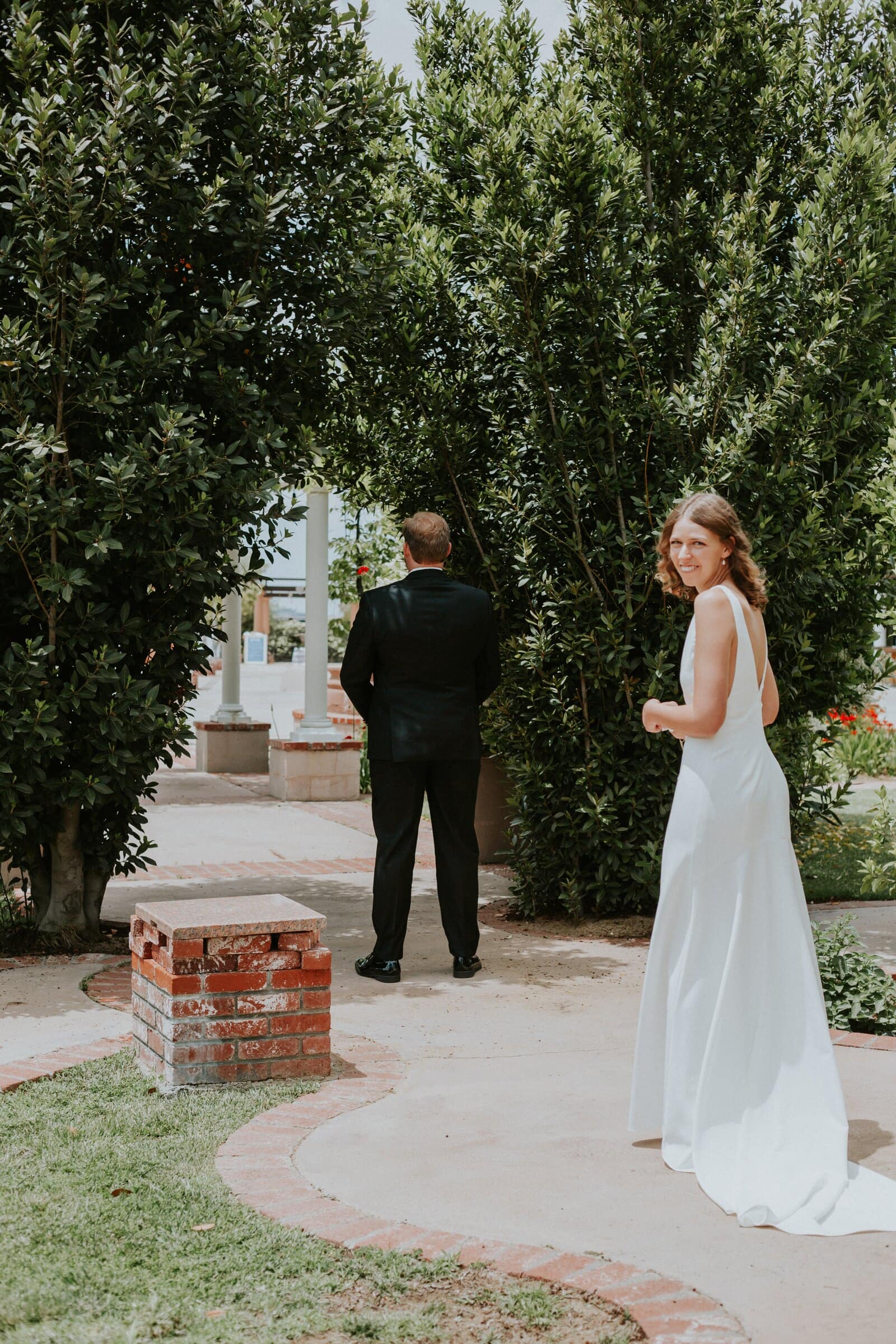 The bride walking up behind the groom for their first look in the garden