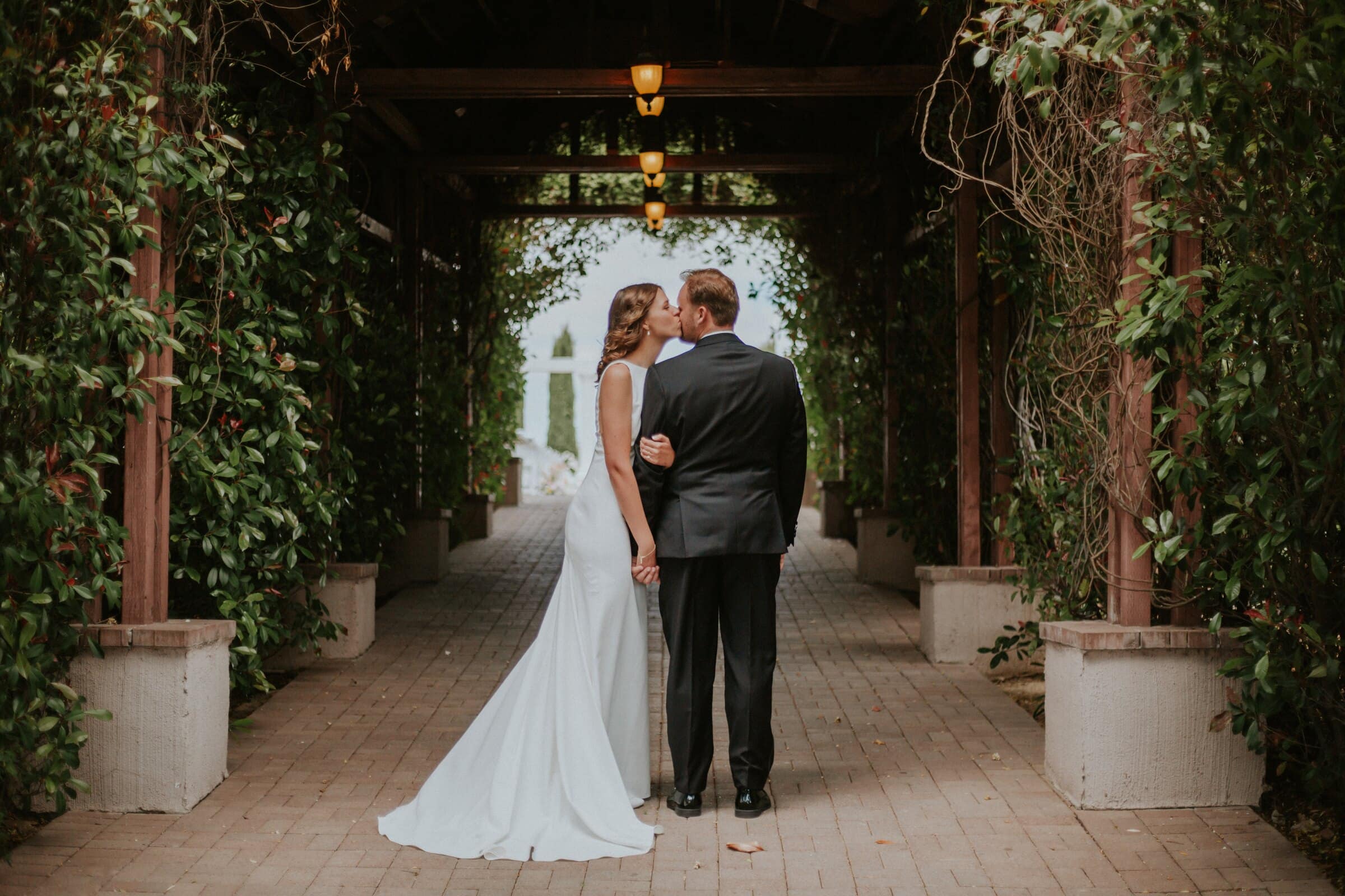 Blake and Ava under a long vine-covered pergola