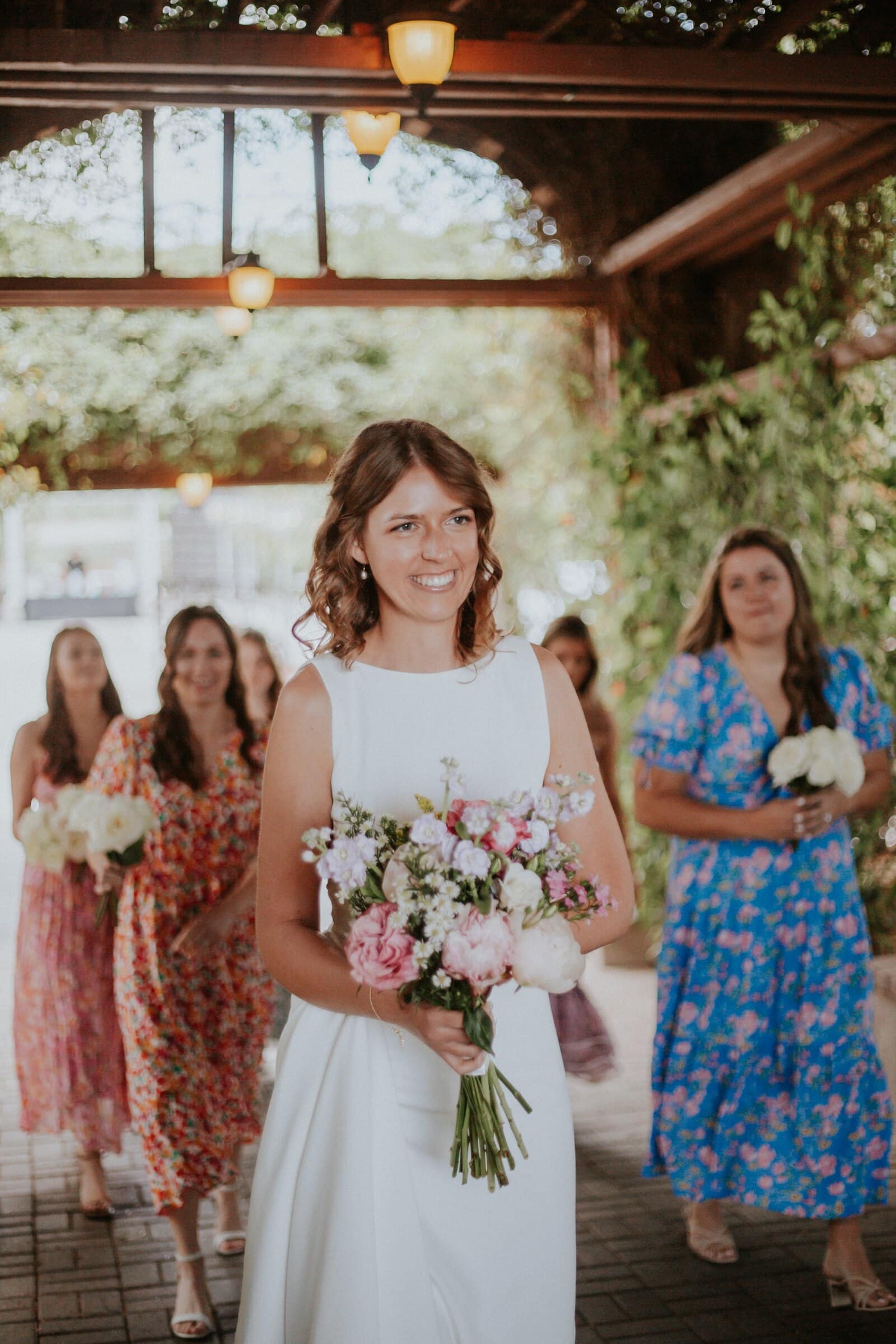 The bride smiling with her bridesmaids in floral dresses