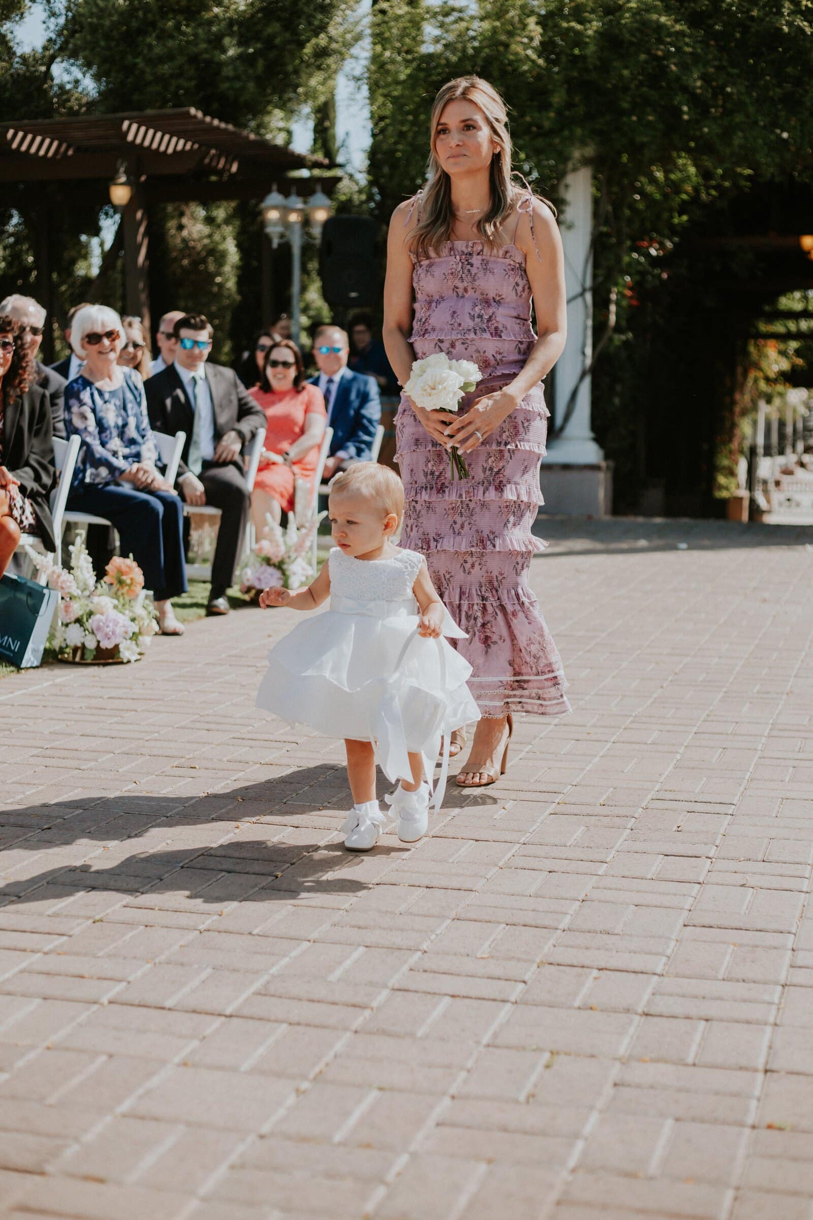 The flower girl walking down the aisle ahead of a bridesmaid