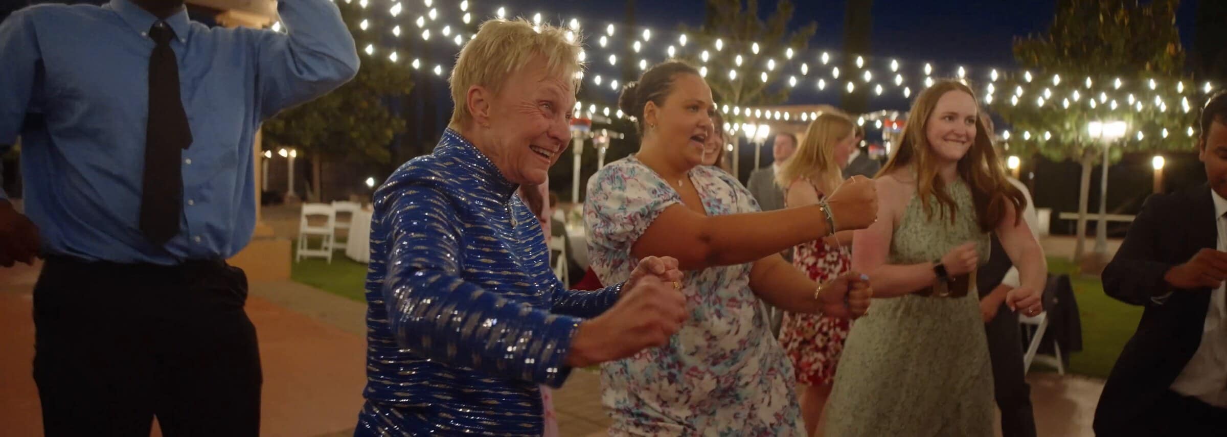 Guests dancing under string lights at night