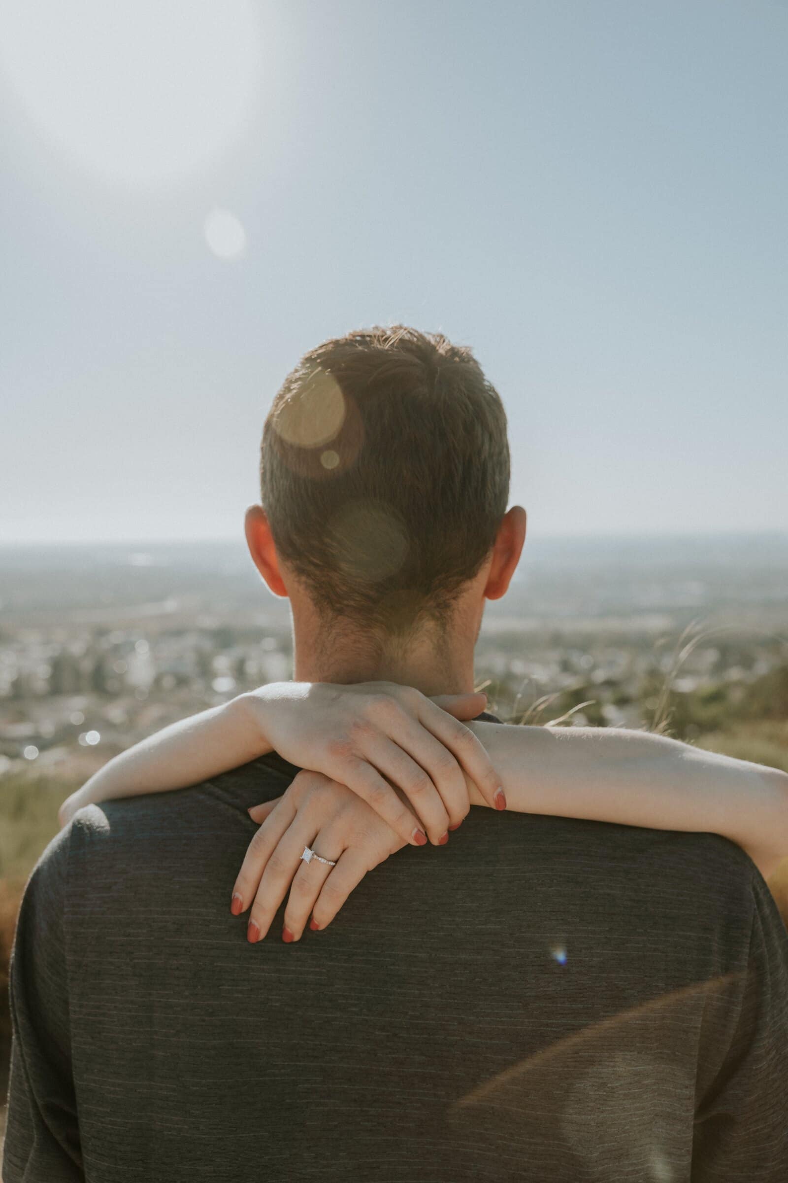 Claire's arms around Bryce's neck, the ring catching the sun
