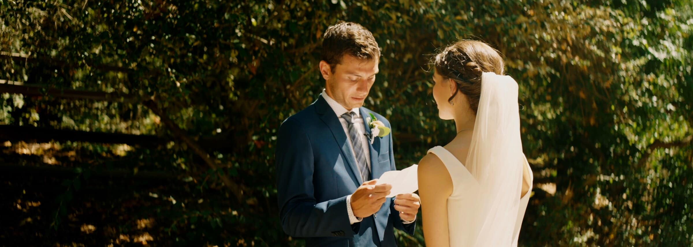 The groom reading his vows to the bride beneath the oaks