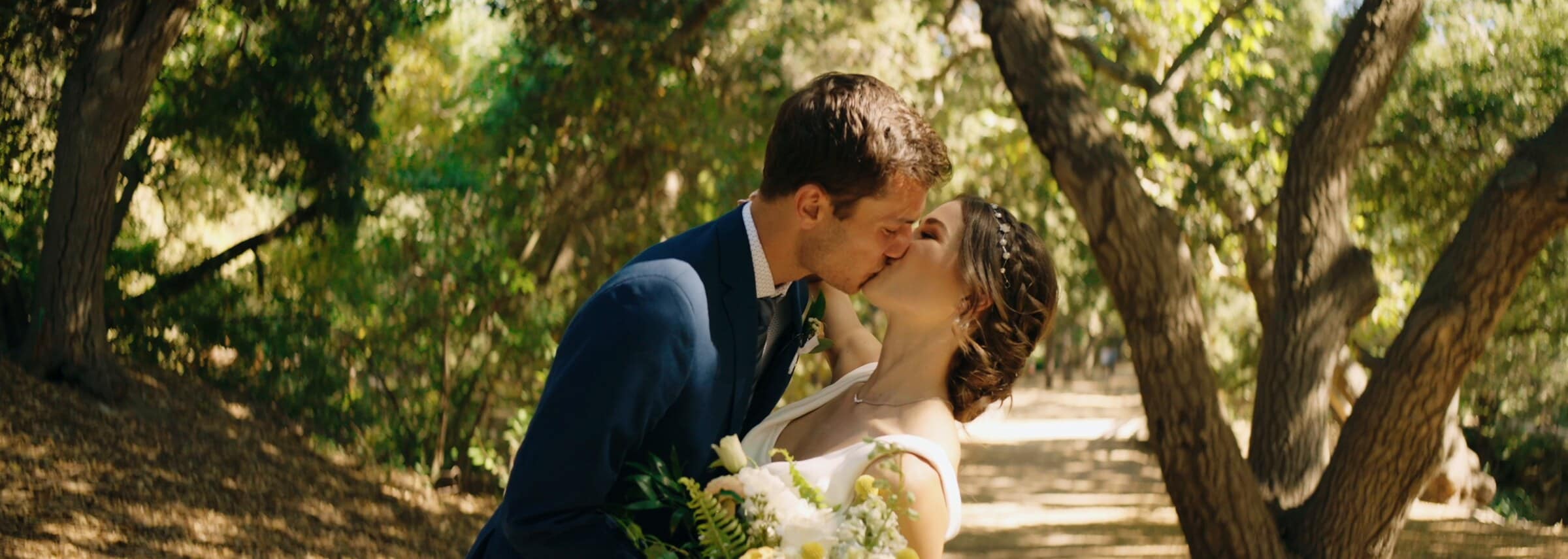 Claire and Bryce kissing in a grove of oak trees