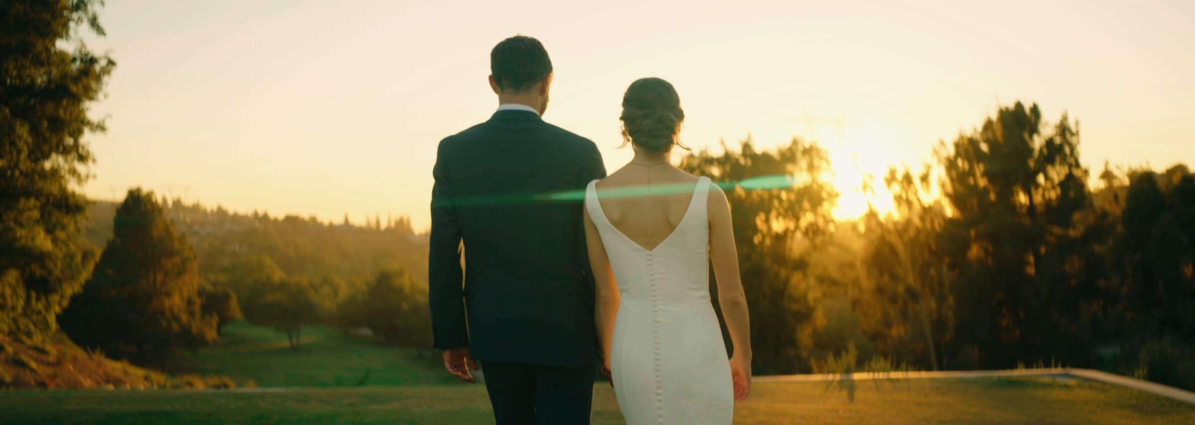 Claire and Bryce walking toward the sunset, seen from behind