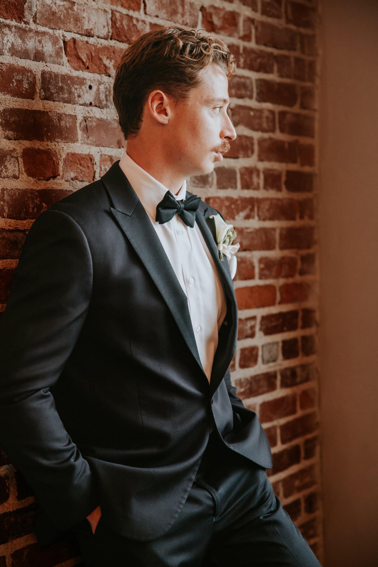 Grant in his tuxedo against a brick wall