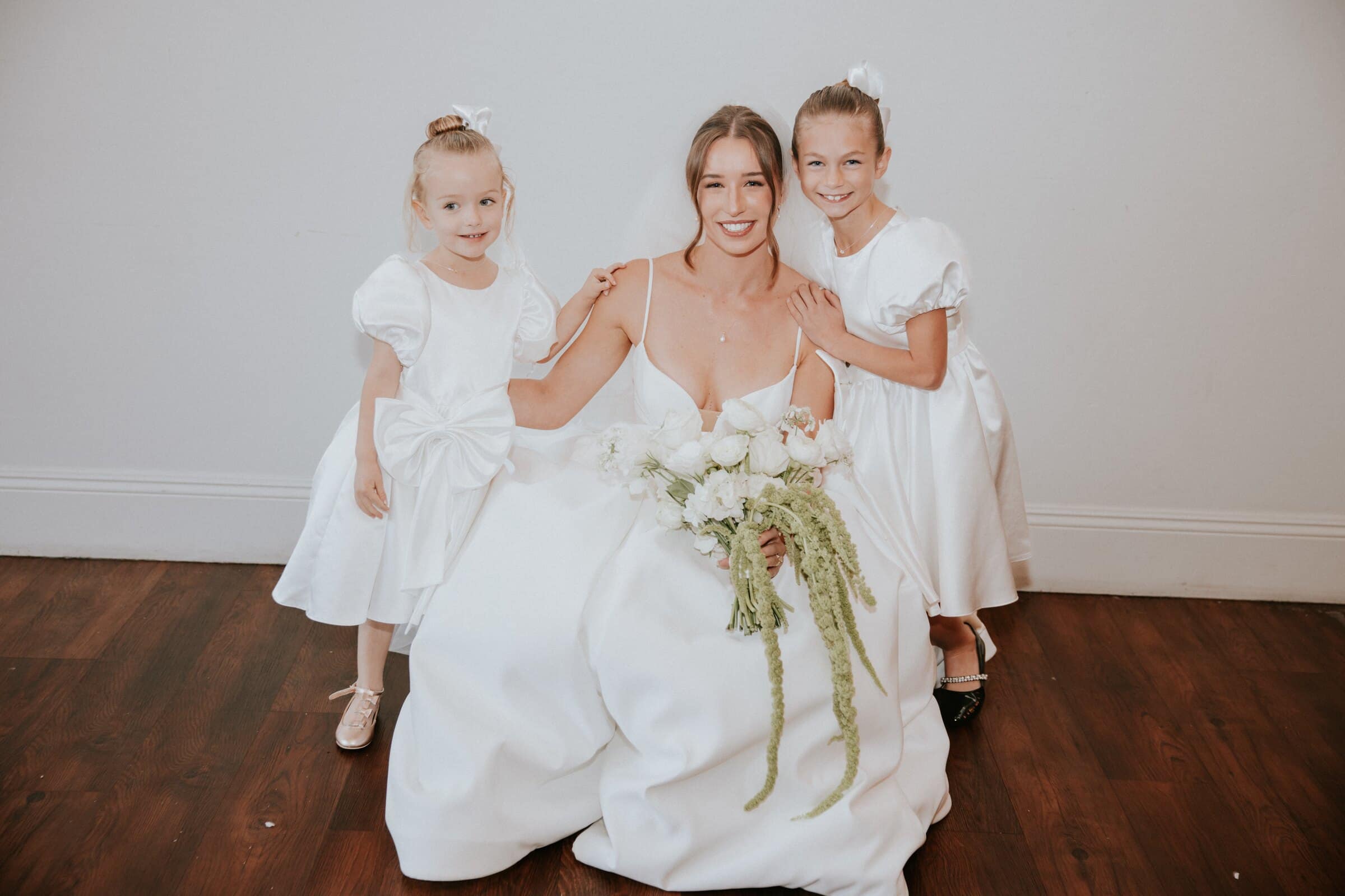 Clara sitting on the floor with two flower girls in white dresses