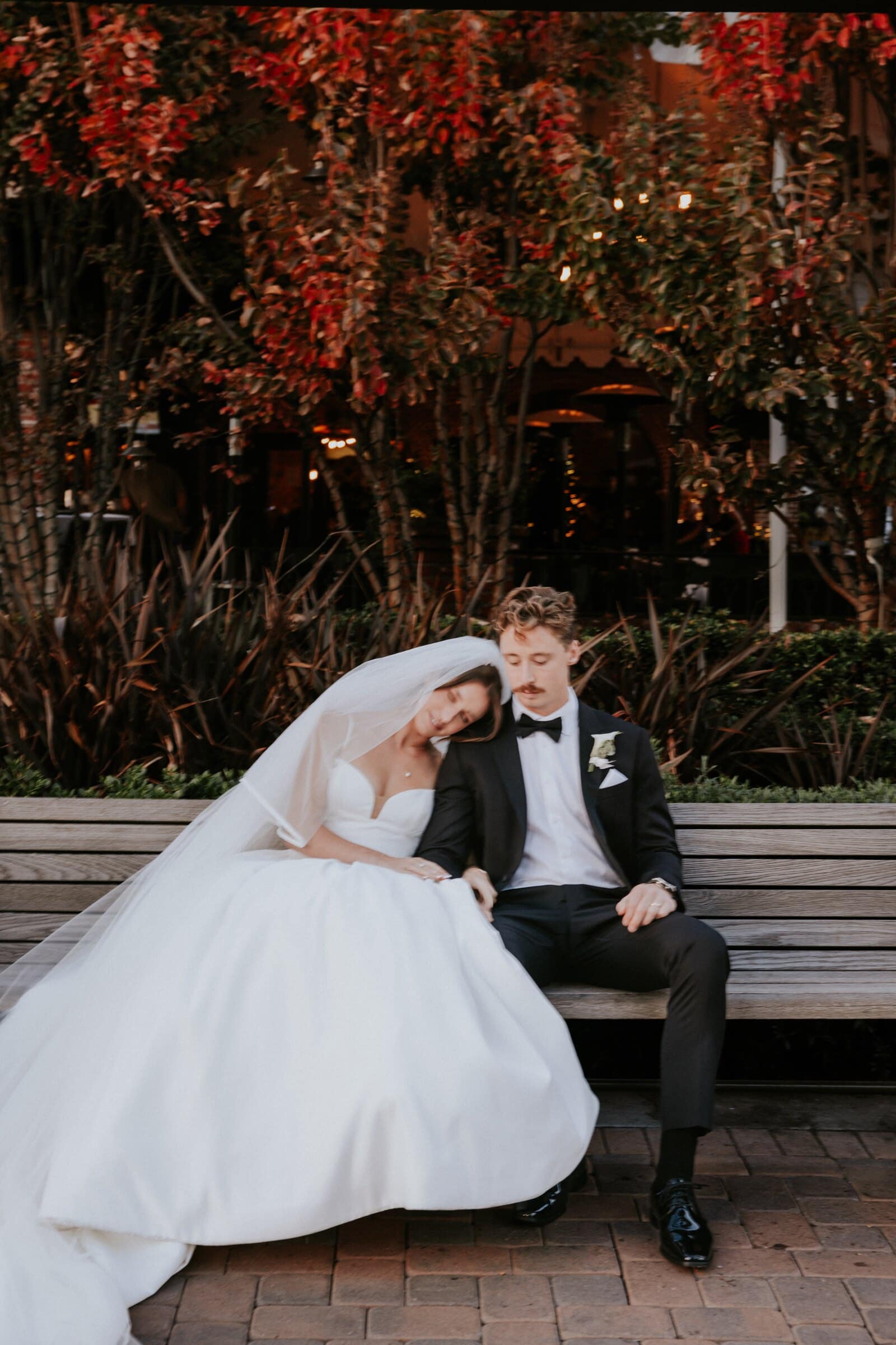 Clara and Grant on a bench under red leaves