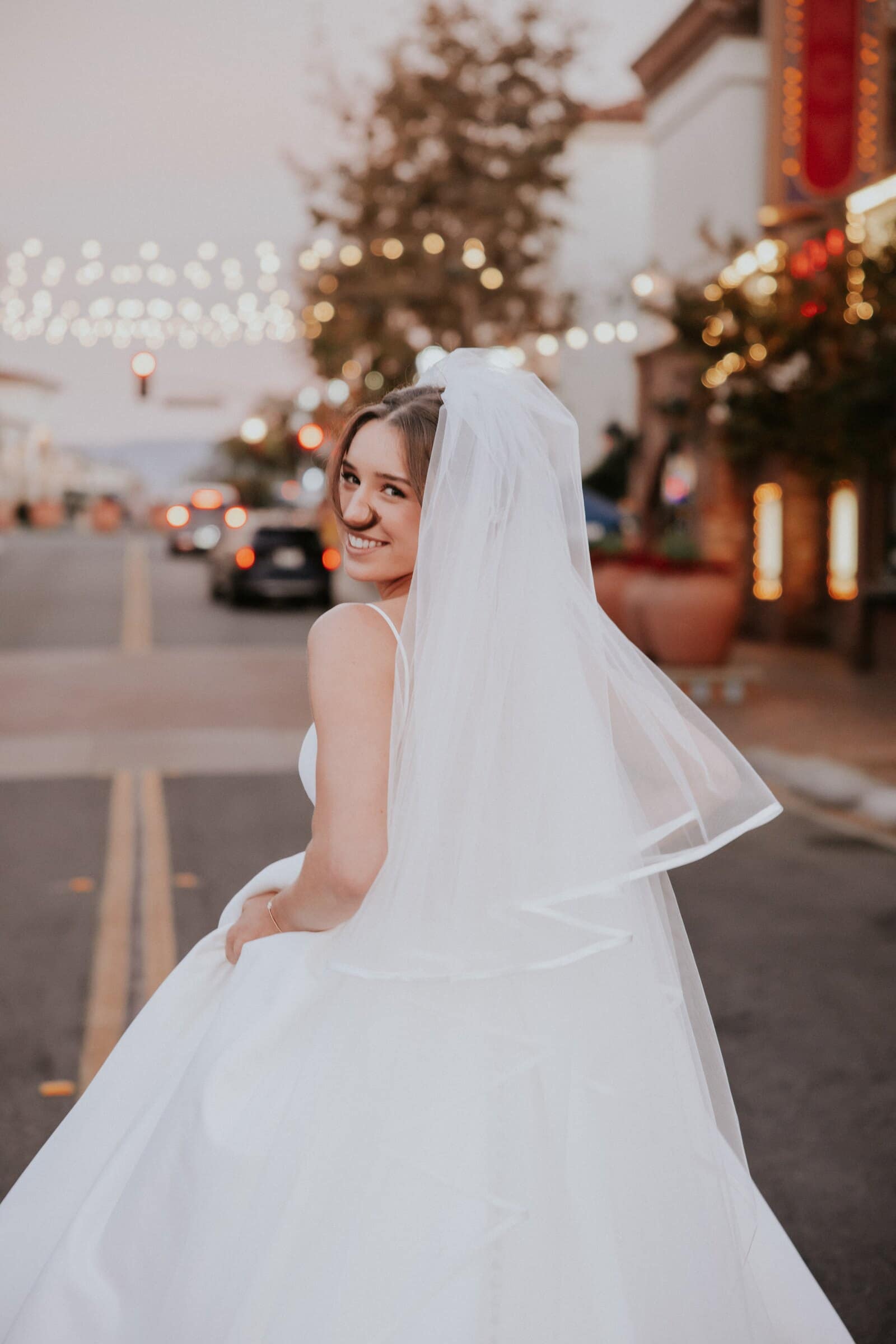 Clara looking back over her shoulder on a street at dusk