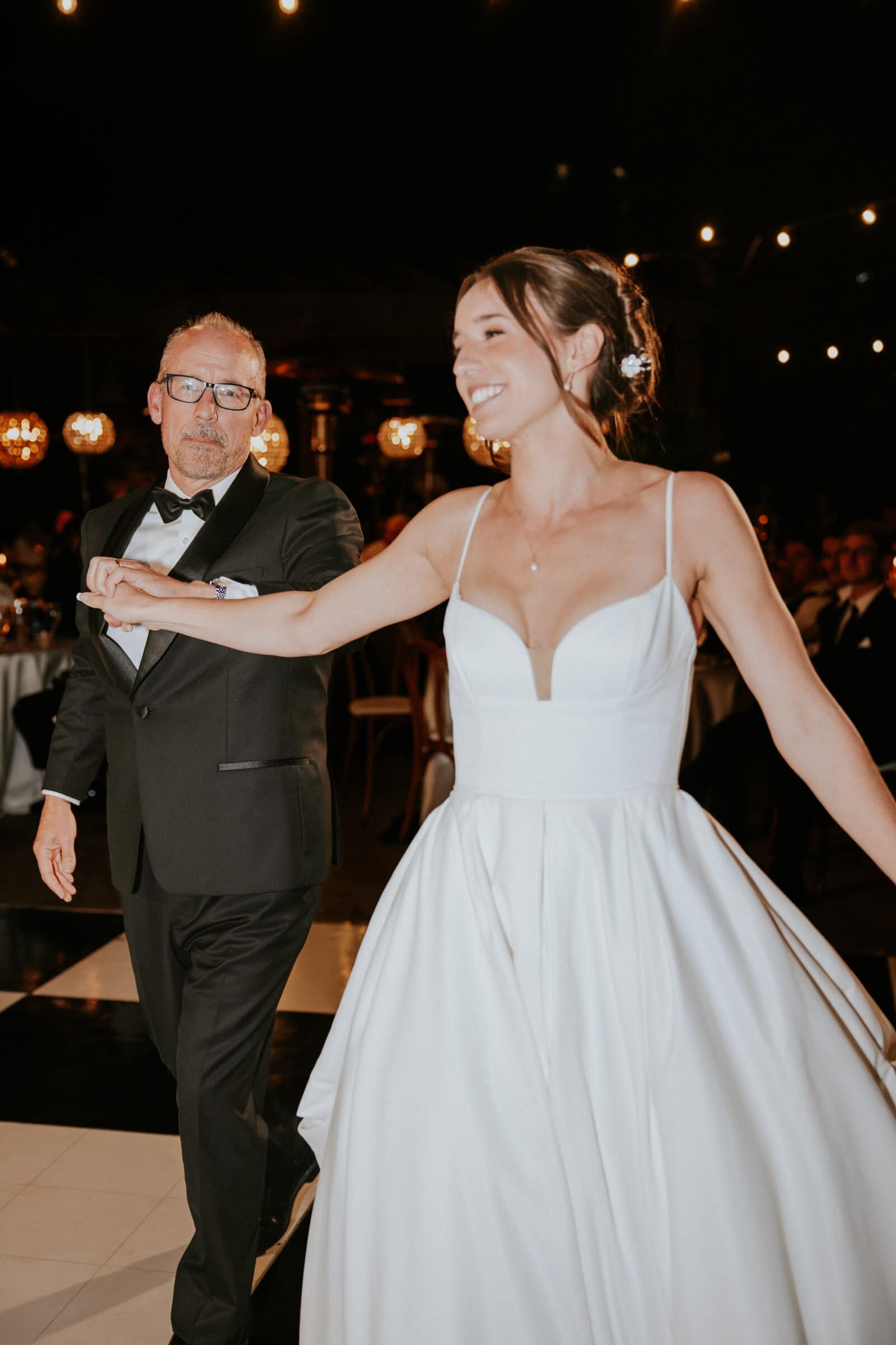 Clara laughing during a dance under string lights