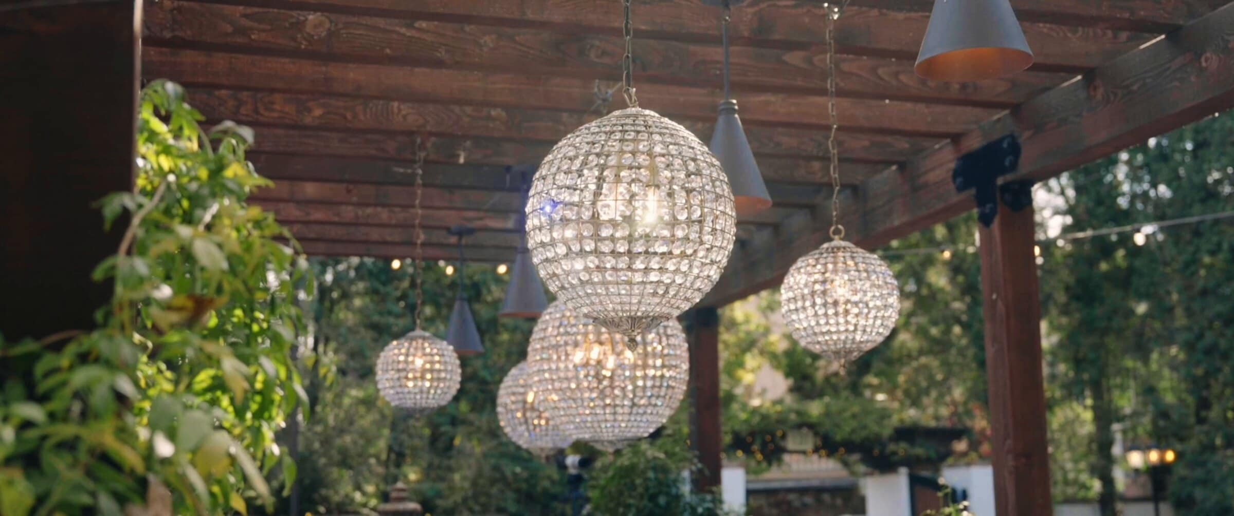 Crystal chandeliers hanging from a wooden pergola over the garden courtyard
