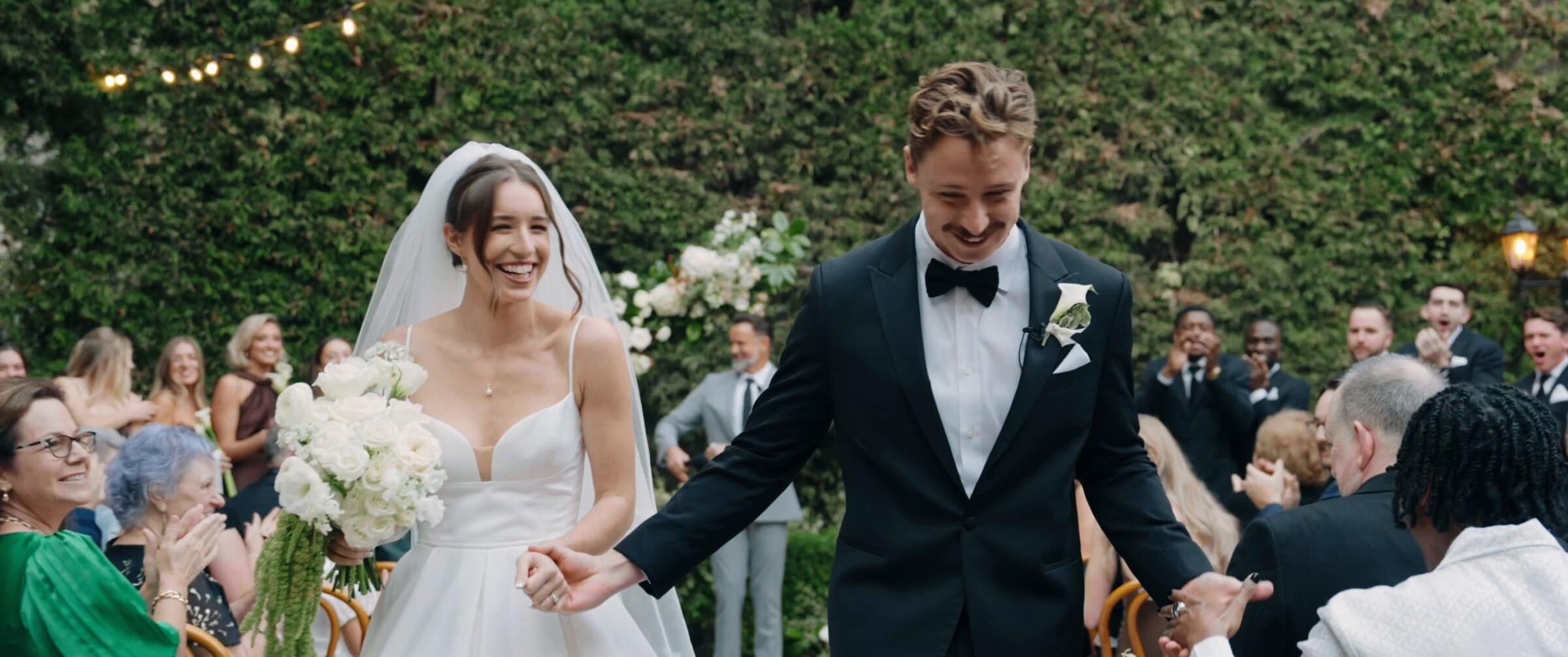 Clara and Grant walking back up the aisle as guests cheer