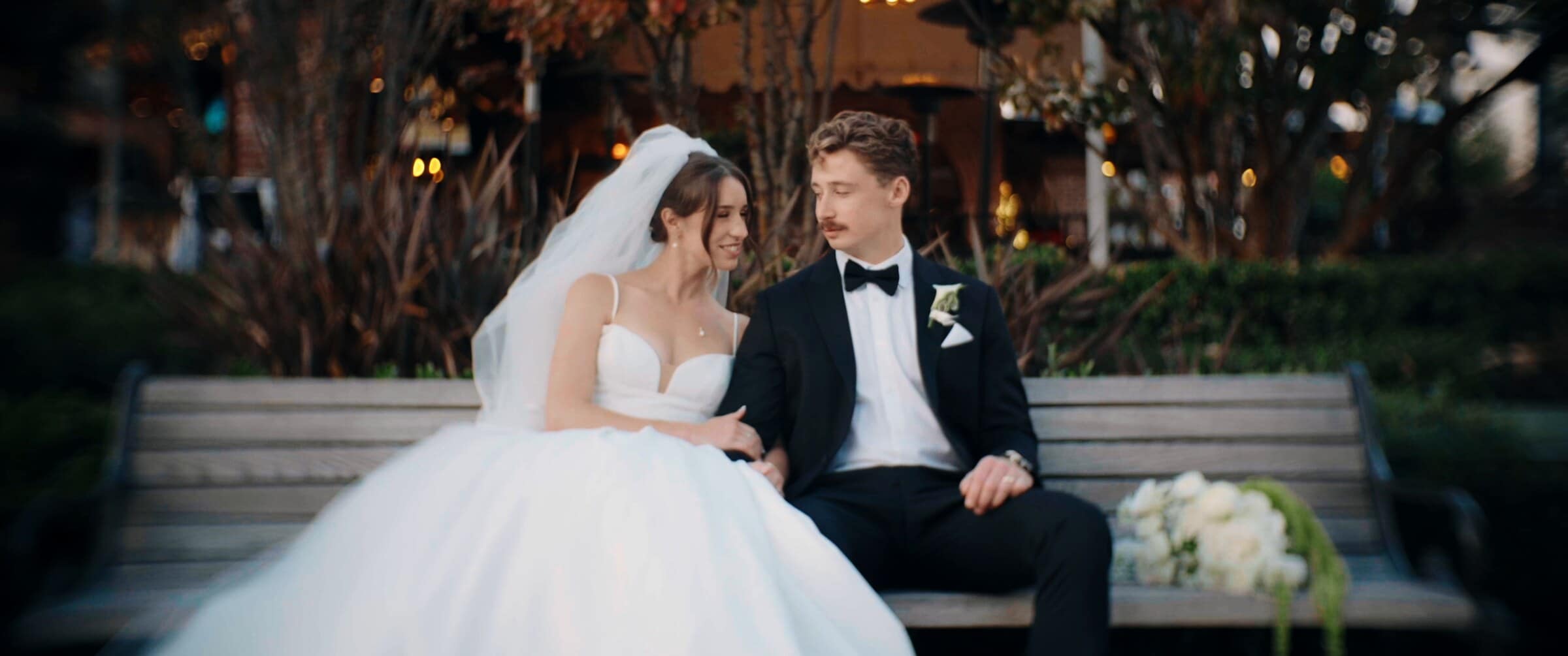 Clara and Grant sitting together on a bench at dusk