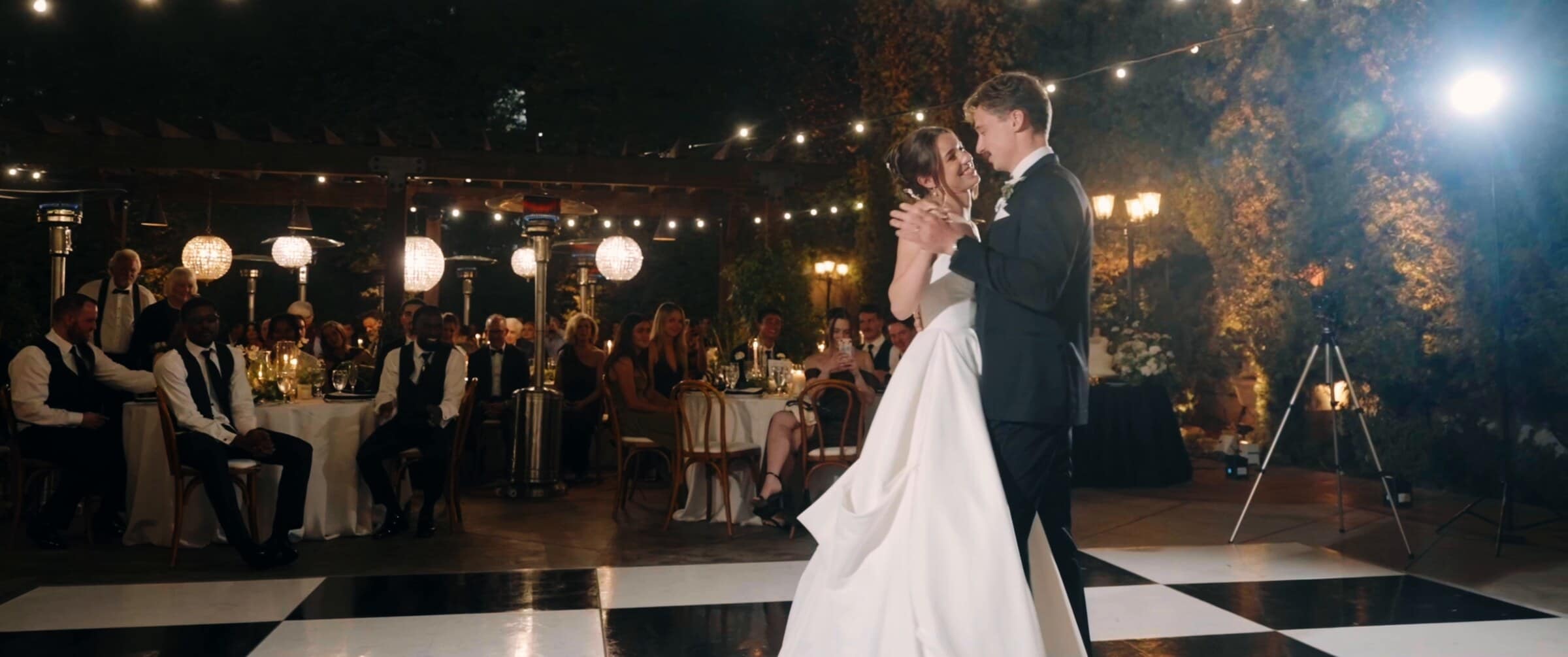 Clara and Grant's first dance on a checkered floor under string lights