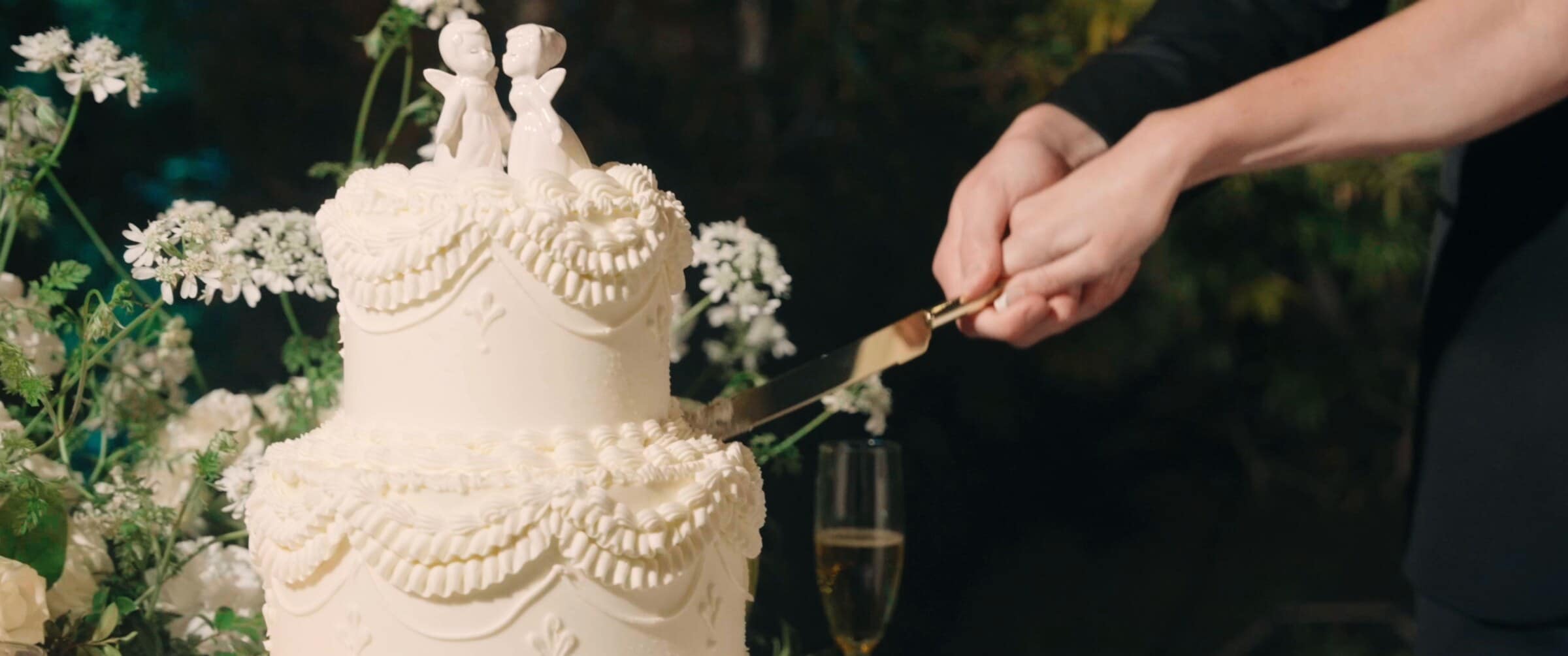 Clara and Grant cutting a white piped wedding cake