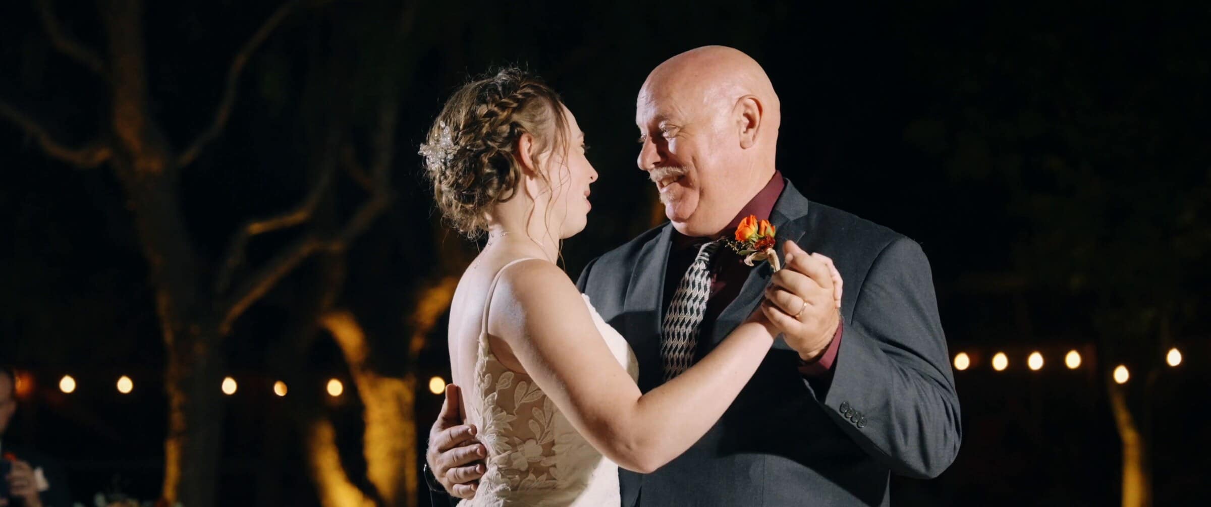 The bride sharing a dance under string lights at night