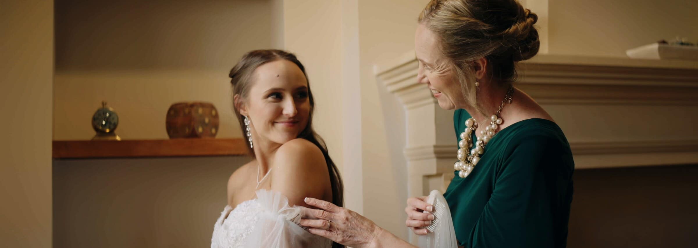 The bride smiling at a woman in green as she gets ready