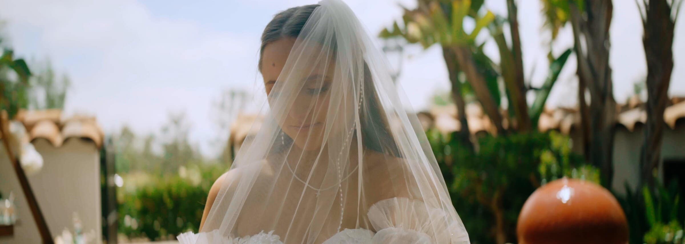 The bride under her veil beside a fountain
