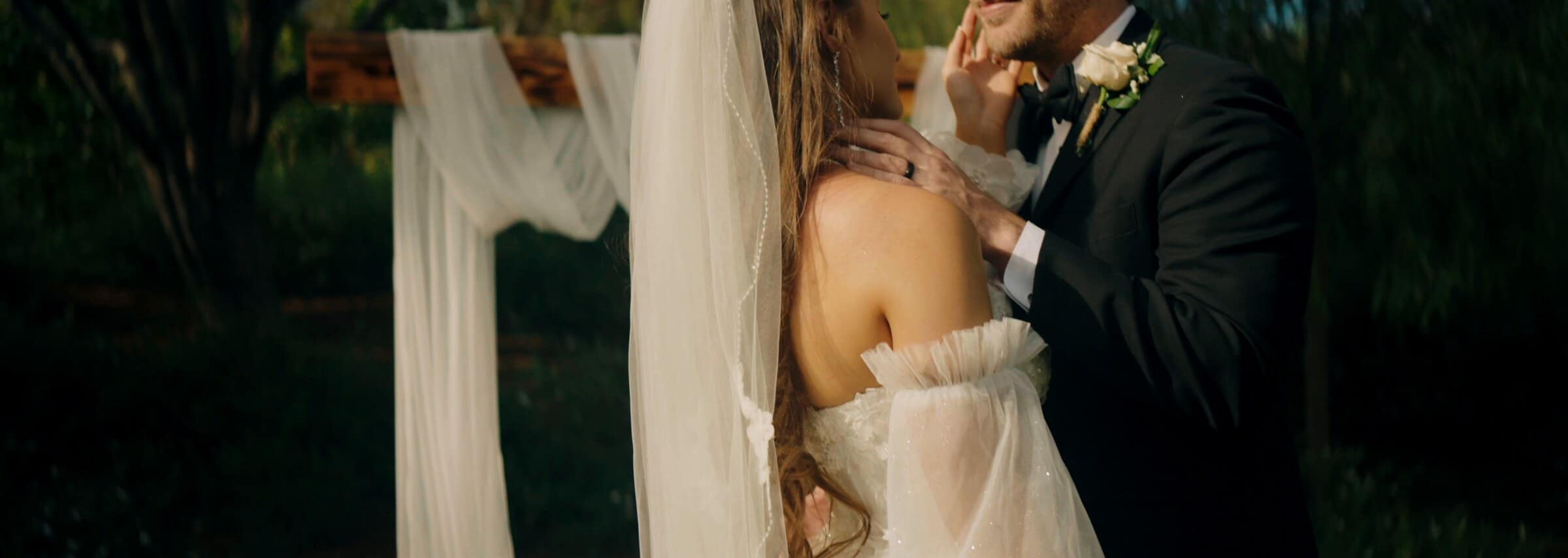 The groom holding the bride close beside the draped cross
