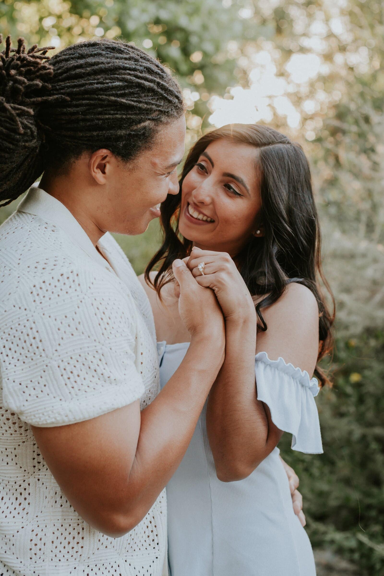 Jeremy and Ambica smiling at each other, hands clasped, in soft backlight