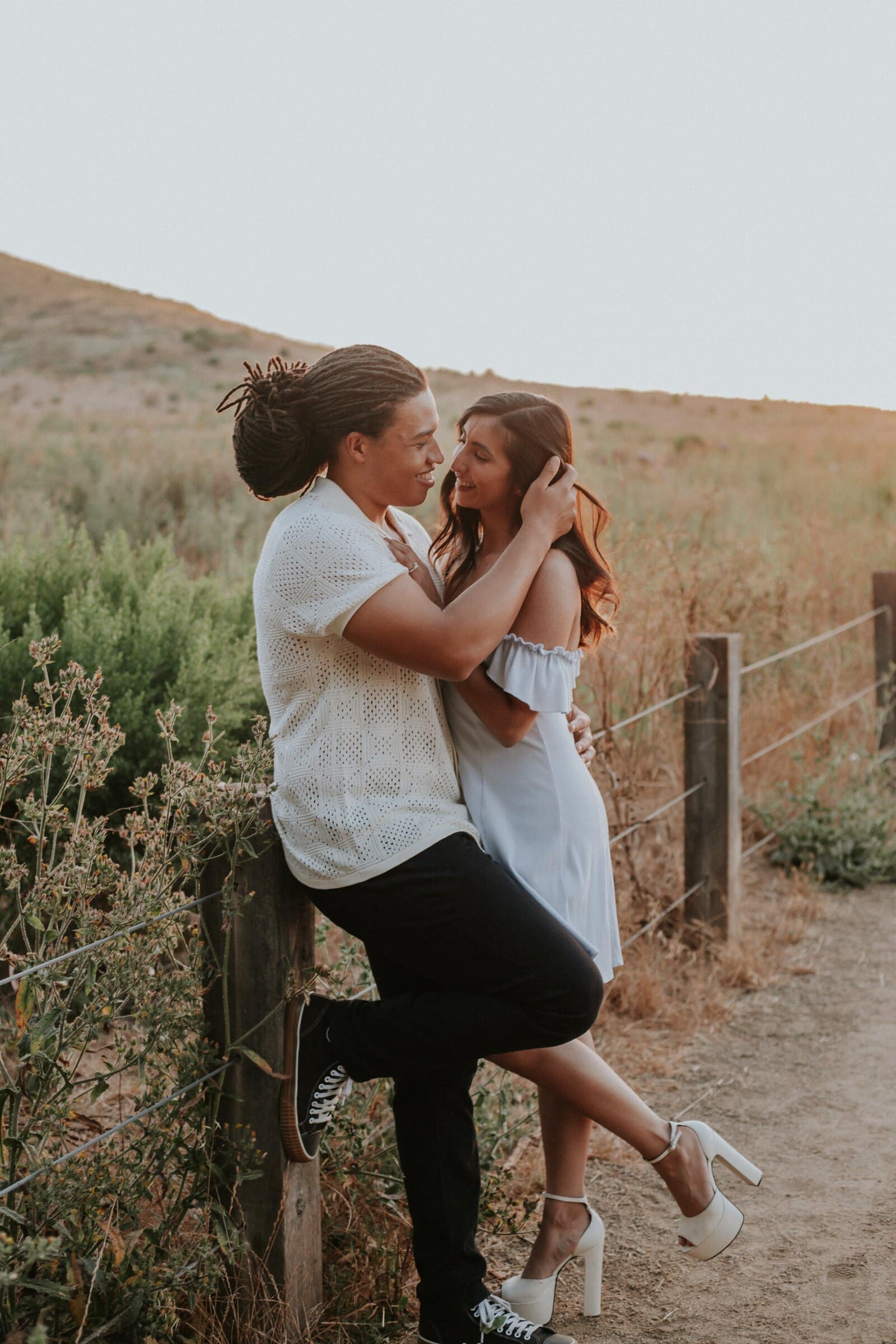 Jeremy and Ambica kissing by a wooden fence