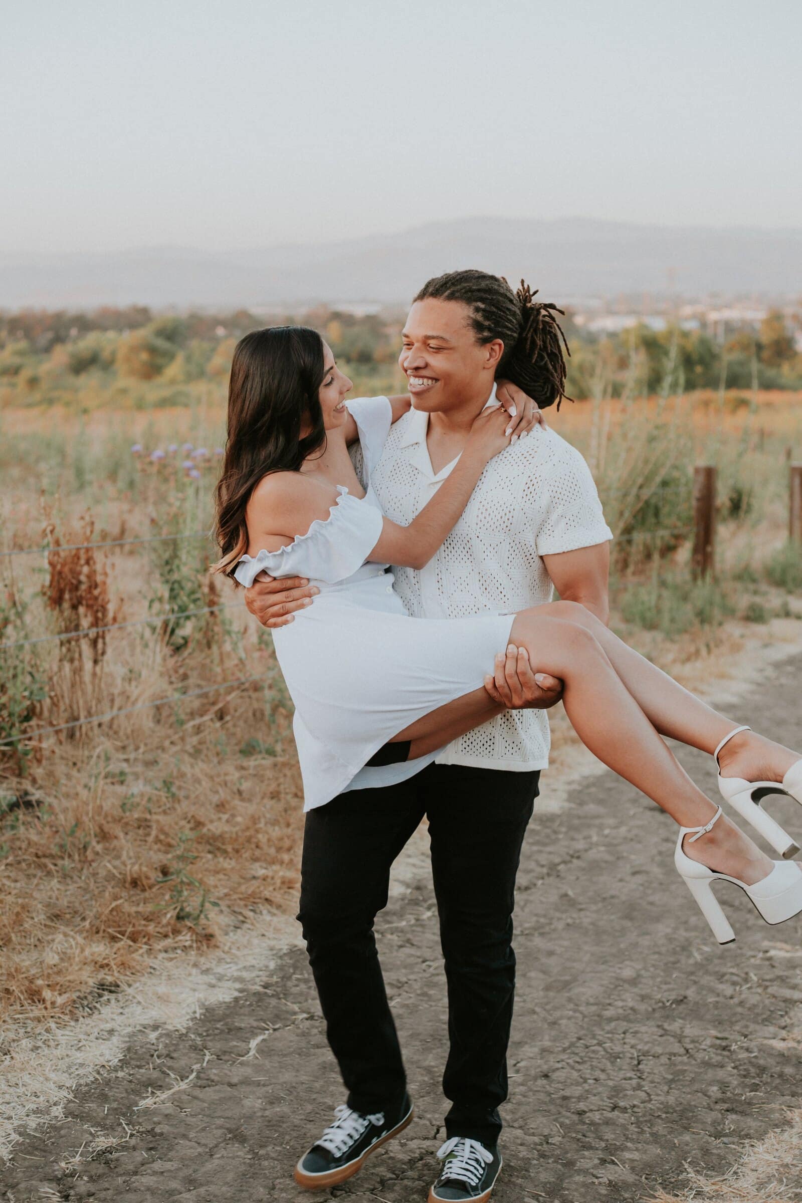 Jeremy carrying Ambica in his arms on a hillside trail