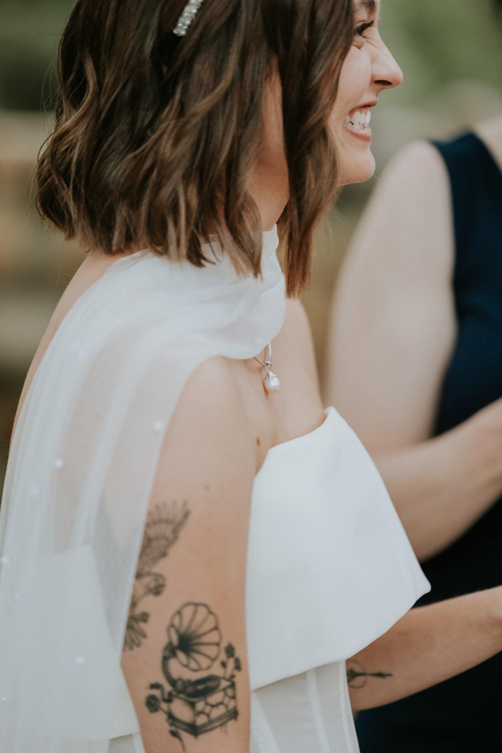 Megan laughing, the tattoo on her arm beside her dress