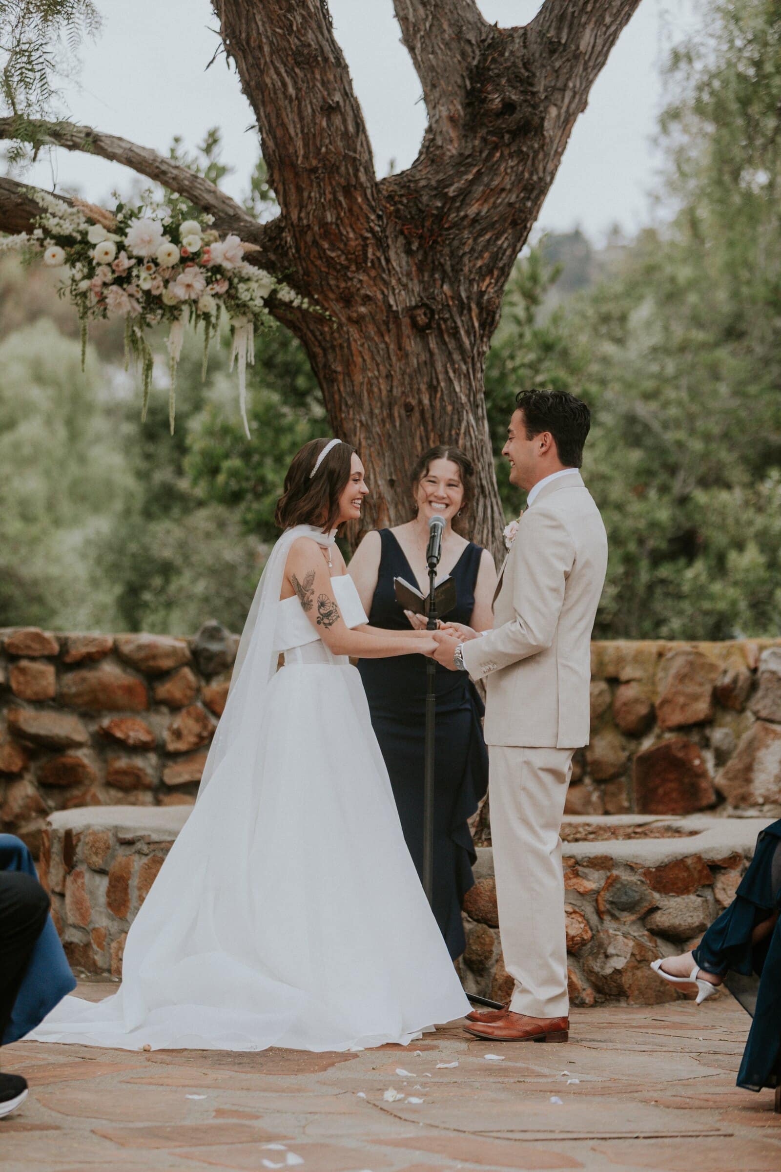 Megan and Caleb holding hands under an old oak during their vows