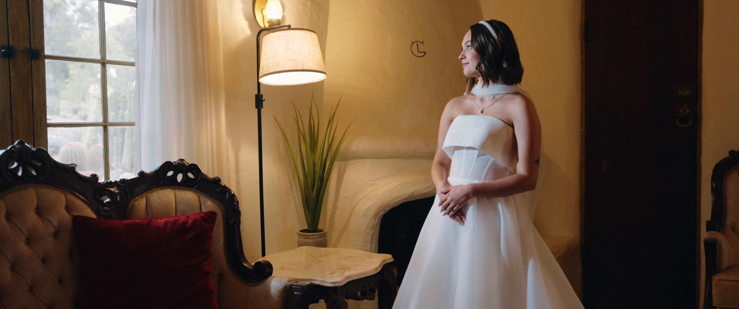 Megan in her dress by a window in a warm, lamp-lit room
