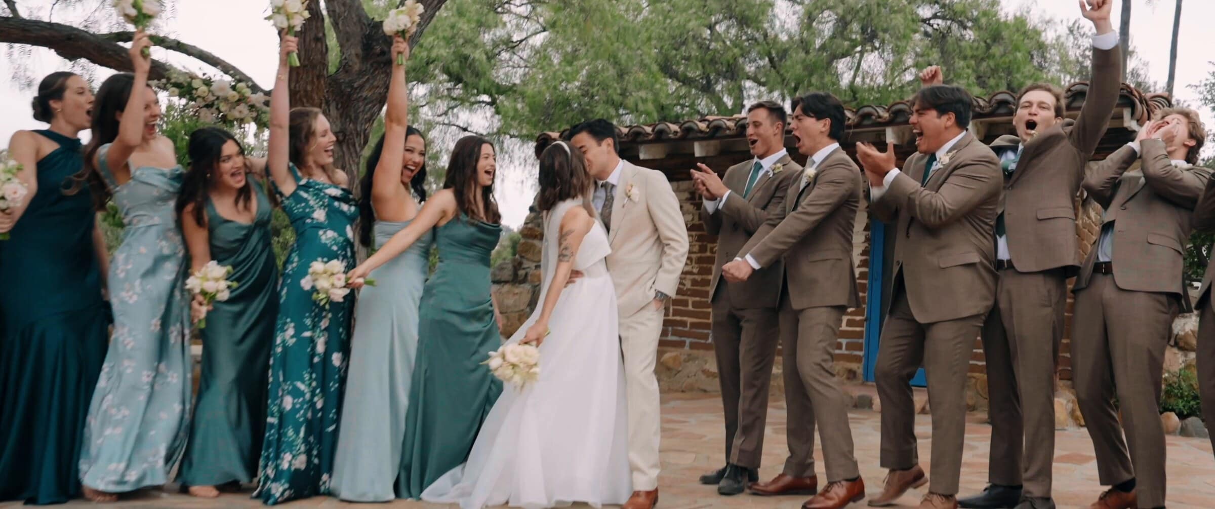 The wedding party cheering as Megan and Caleb kiss