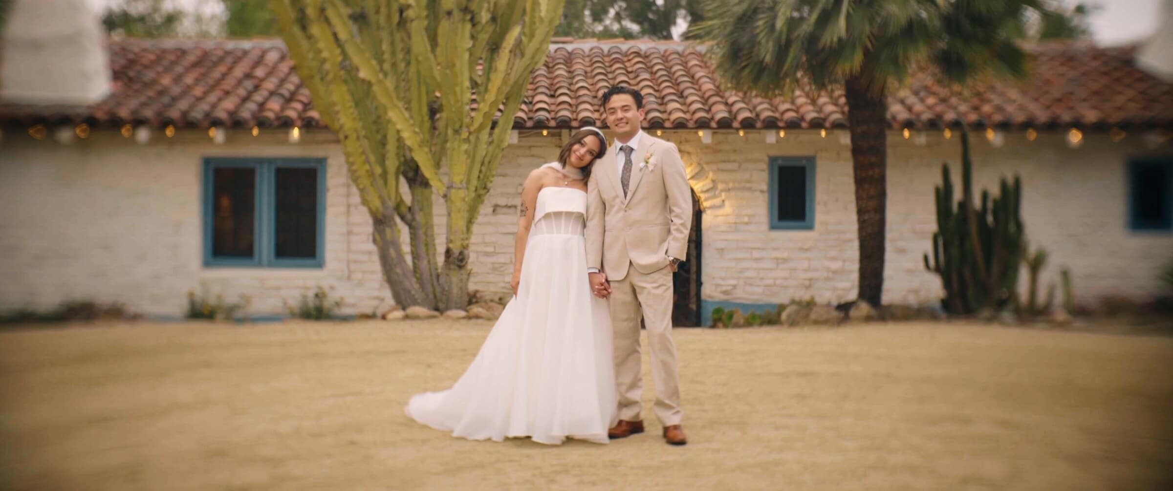 Megan and Caleb in front of an adobe ranch house with a red tile roof