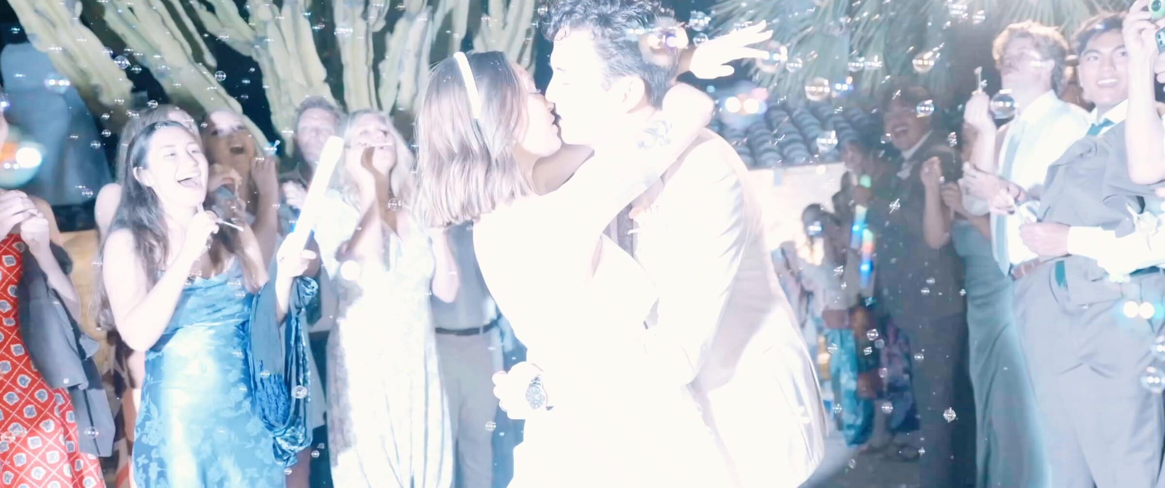 Megan and Caleb kissing on a crowded dance floor full of bubbles