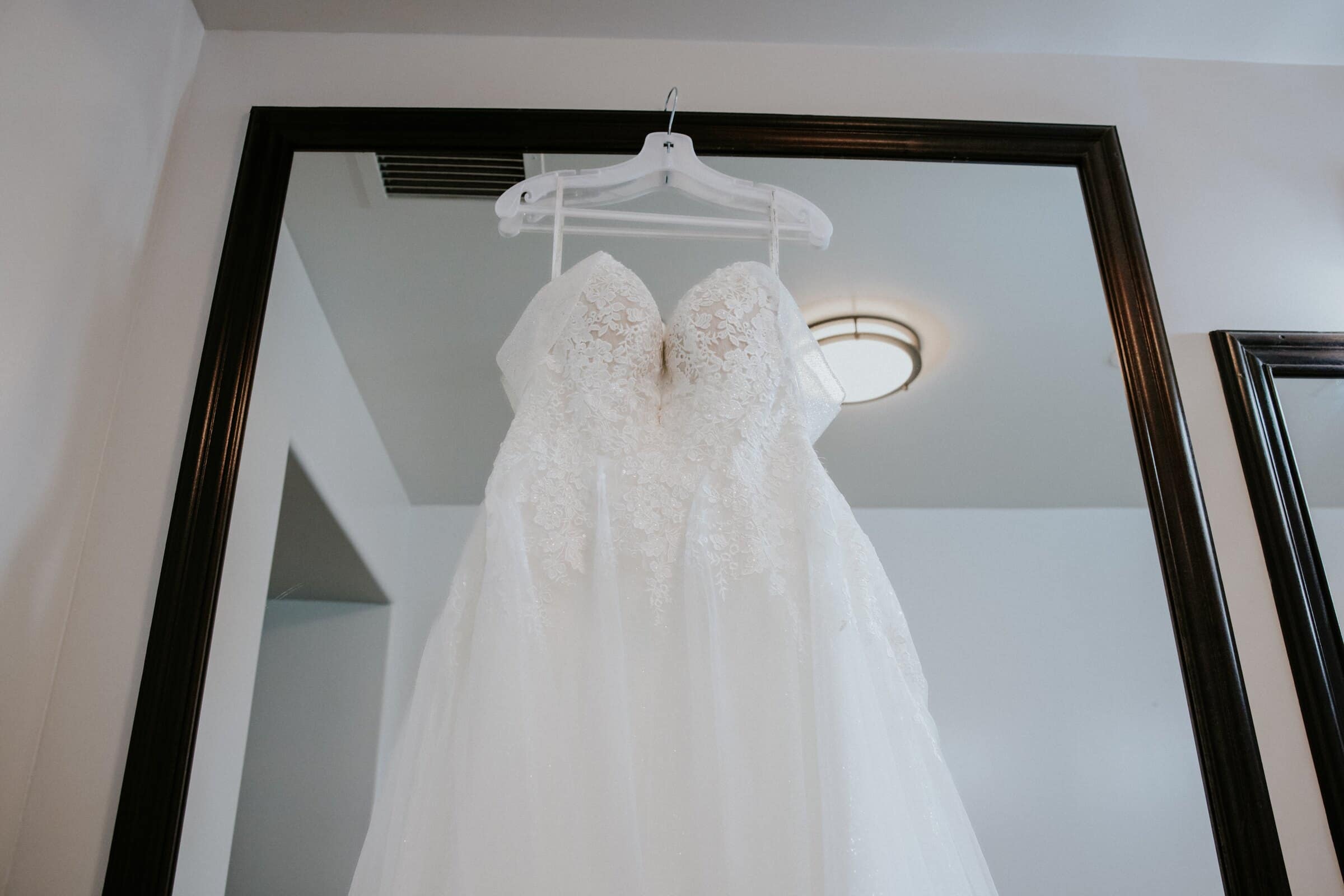 Natalie's wedding dress hanging in front of a mirror