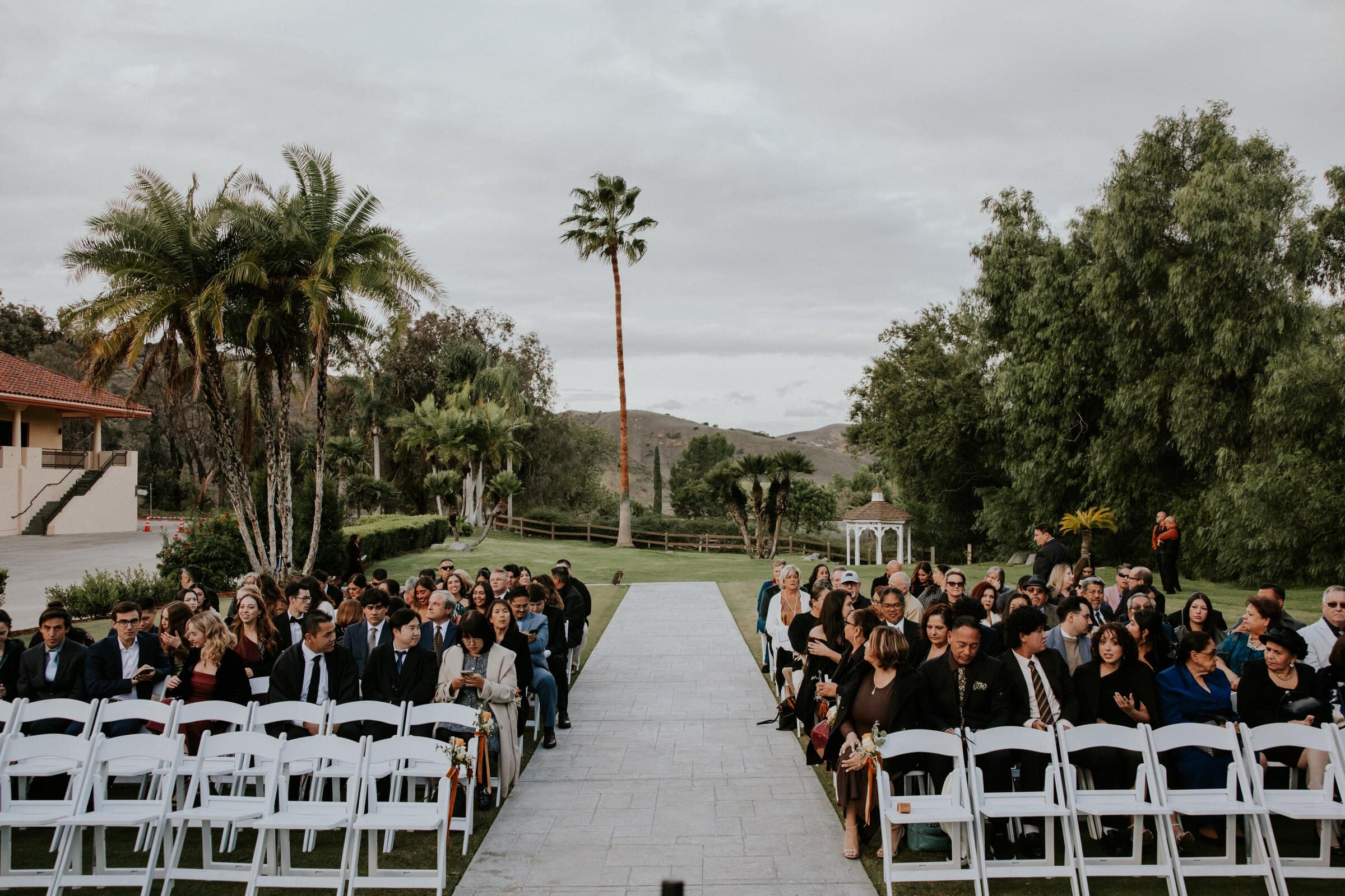 Guests seated on the lawn on either side of the aisle