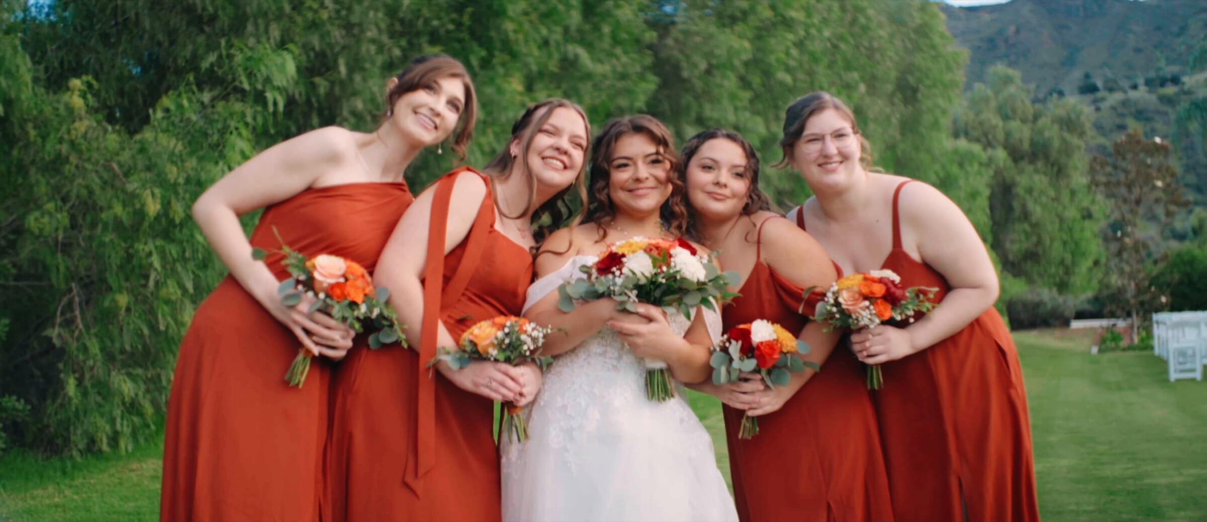 Natalie laughing with her bridesmaids in rust-red dresses