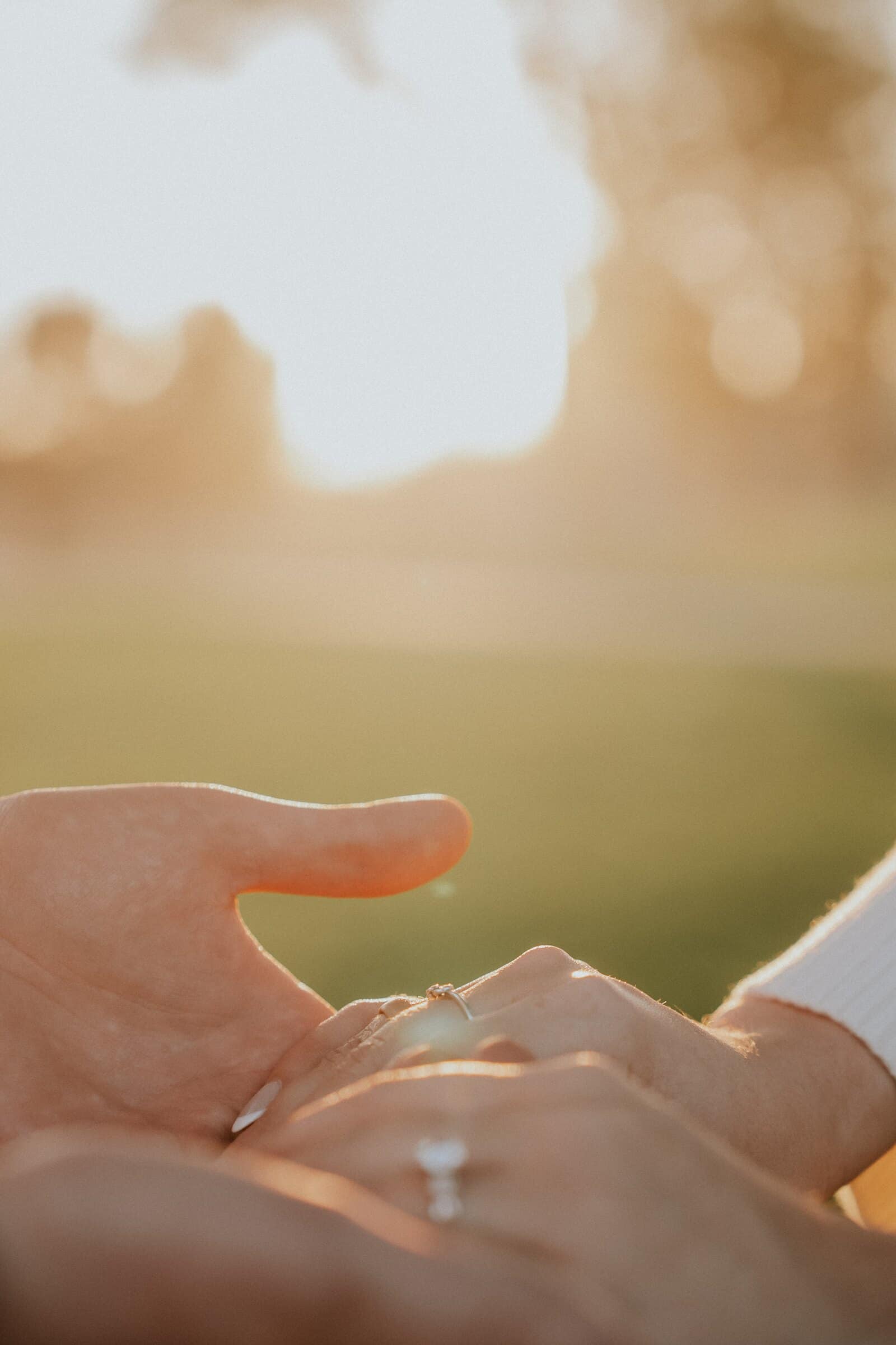 The engagement ring catching the low sun as their hands touch