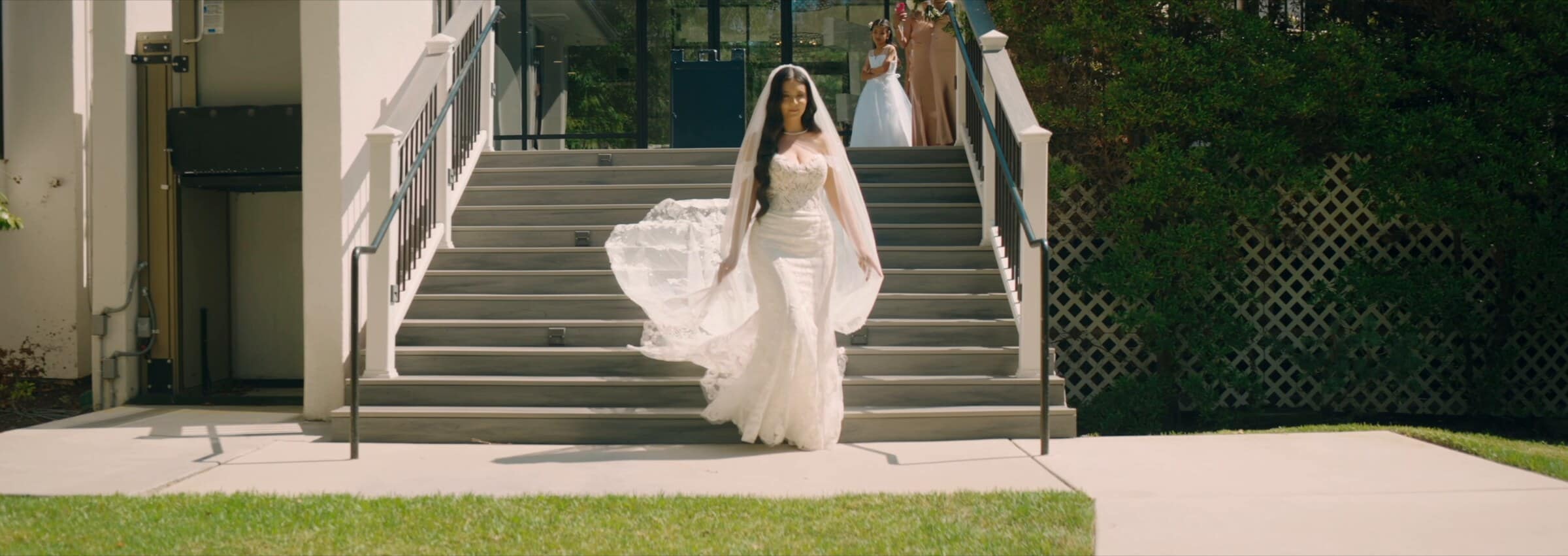 The bride coming down a flight of stairs, her veil trailing behind her
