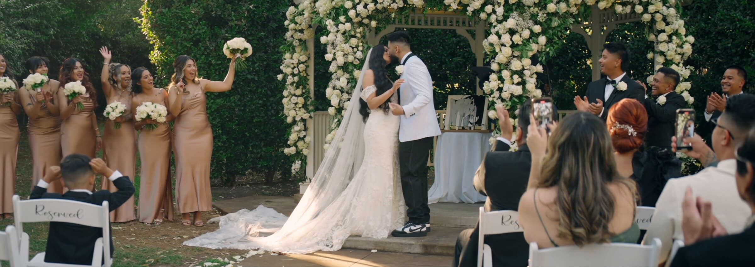 Rubi and Francis kissing under a gazebo covered in white flowers