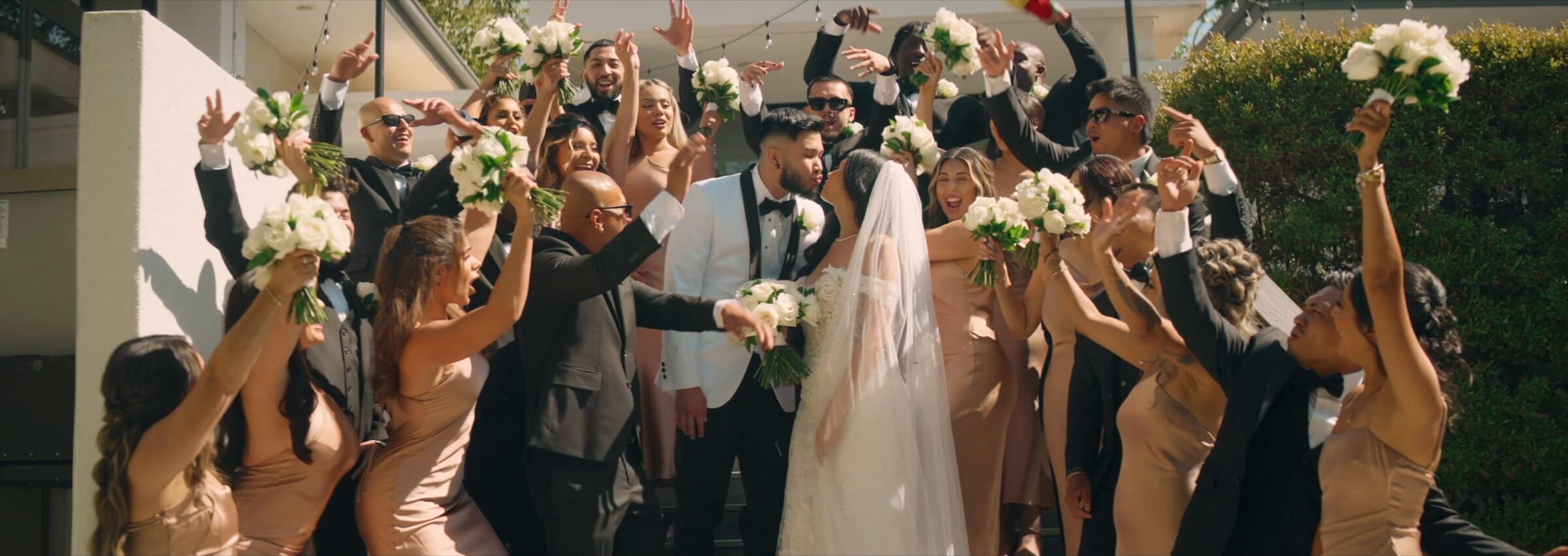The wedding party cheering with bouquets in the air