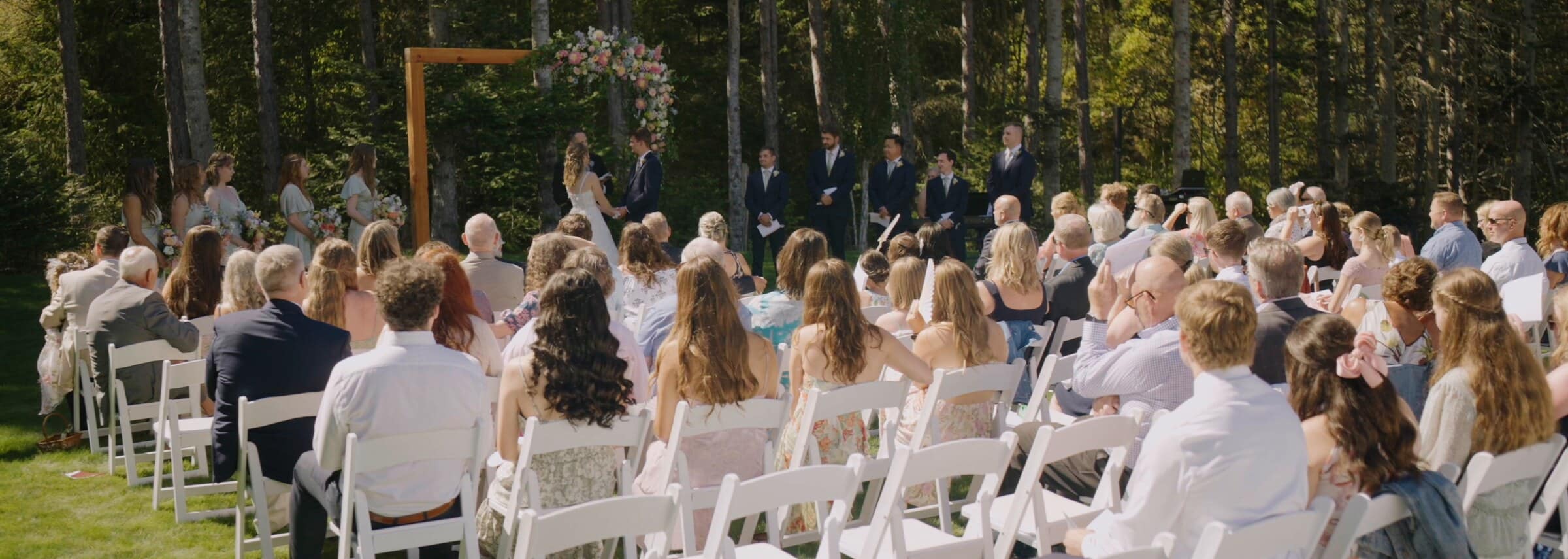 Guests seated in rows facing Sarah and Trent's ceremony among the trees