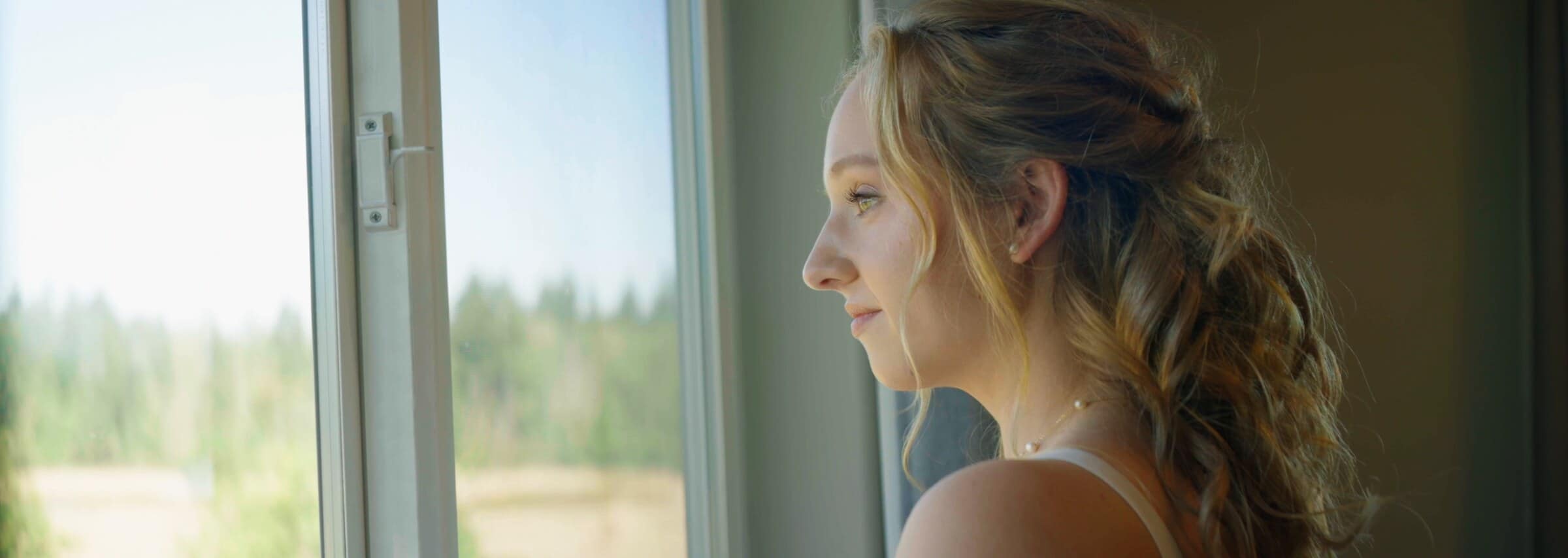 The bride looking out a window in soft light