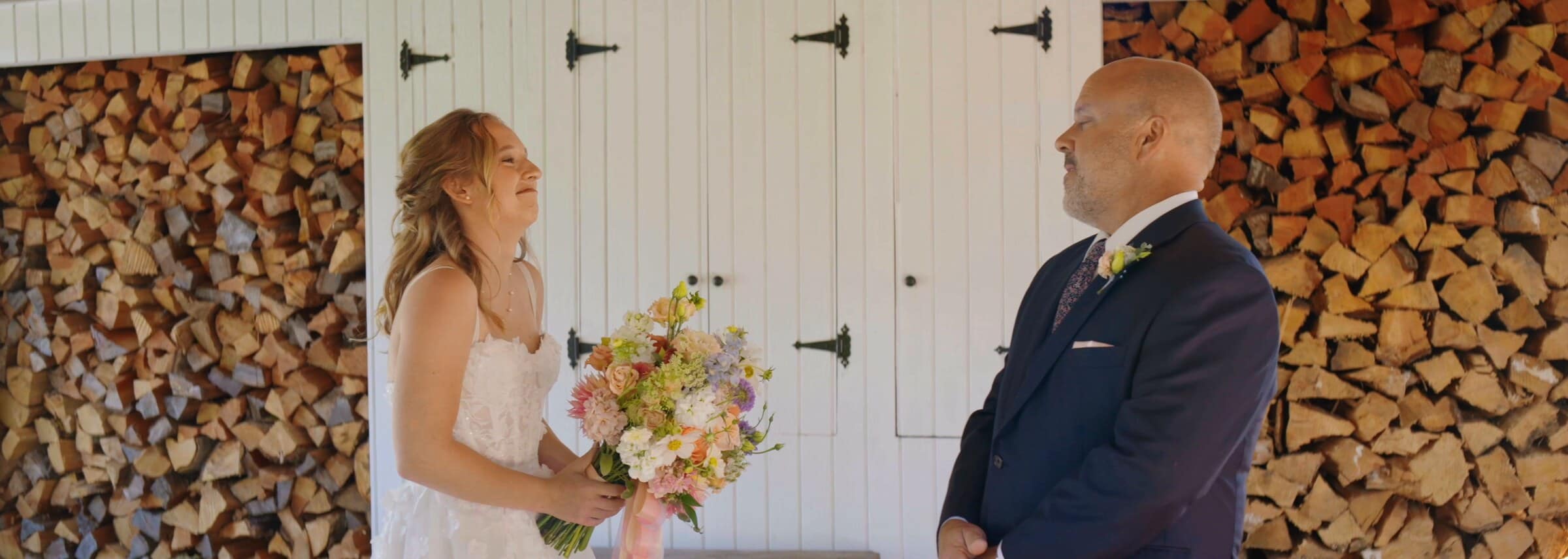 A first look in front of a stacked woodpile and white barn doors