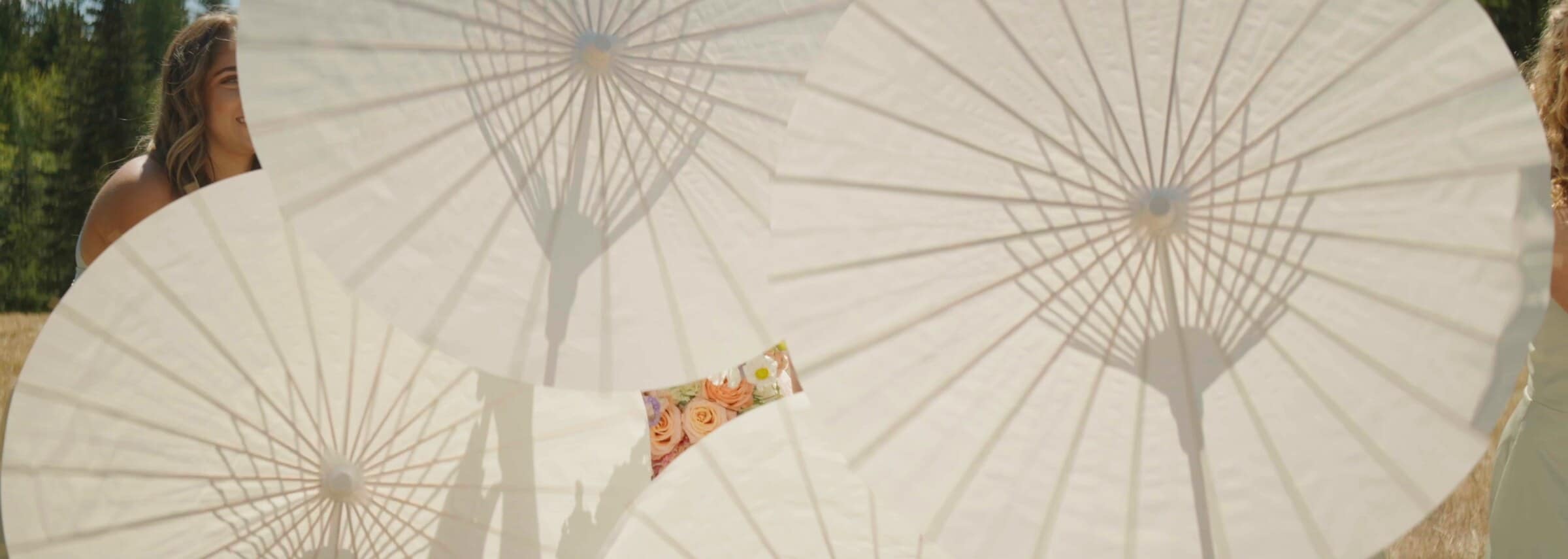 White paper parasols held by the bridesmaids