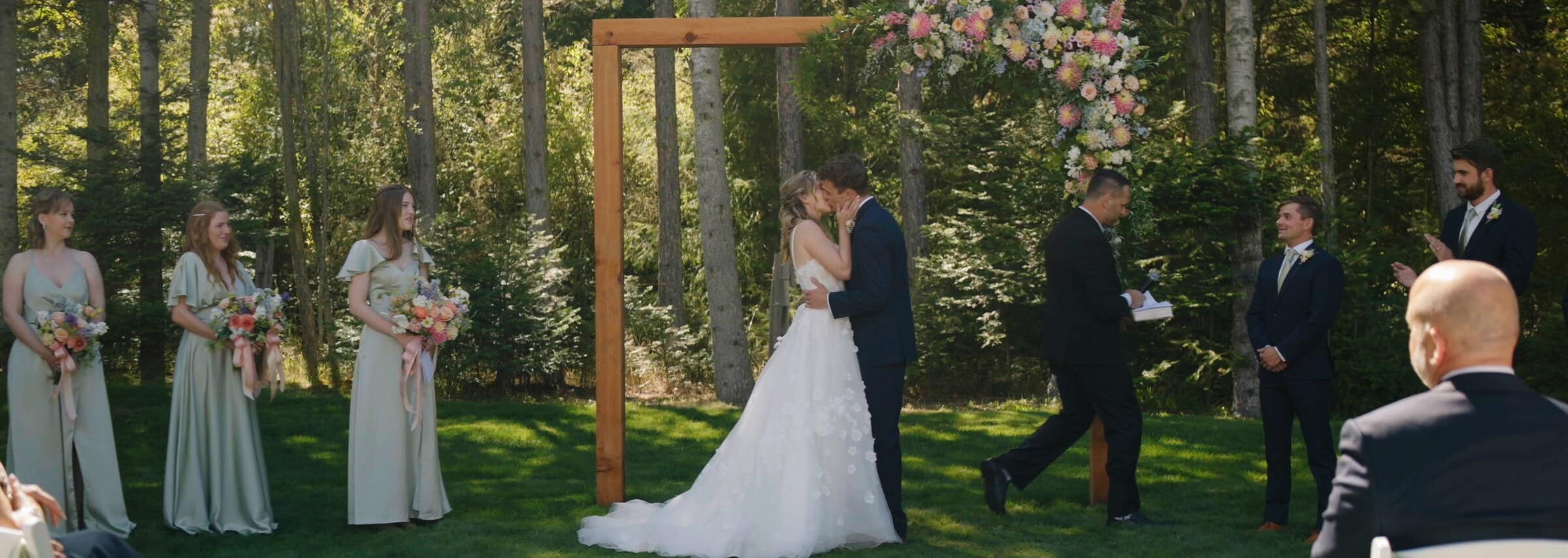 Sarah and Trent's first kiss beneath a wooden arbor in the trees