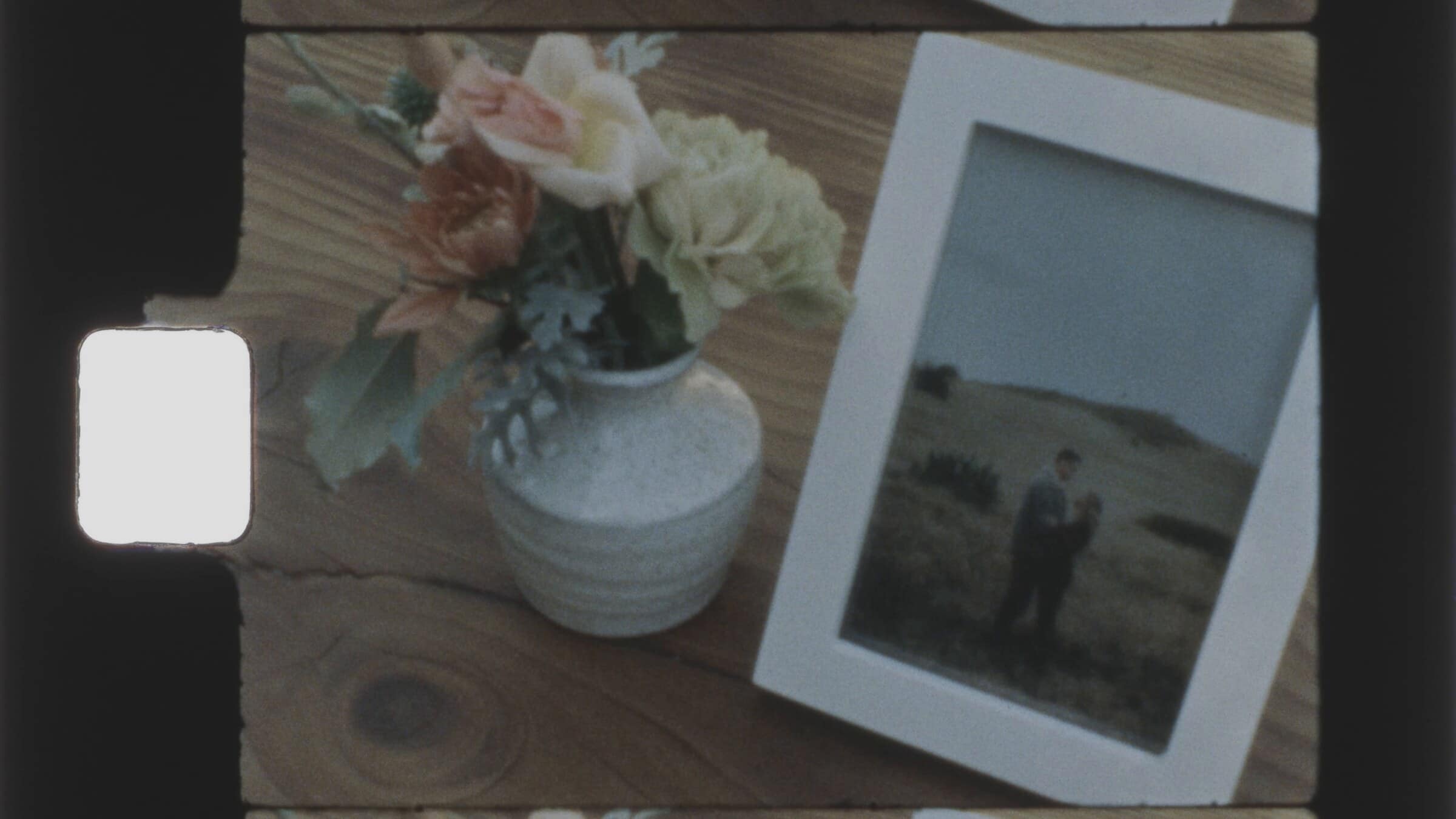 A framed photograph beside a small vase of flowers
