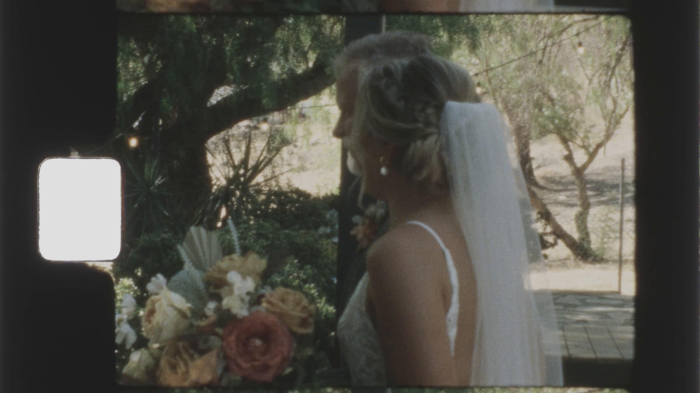 The bride in her veil holding a bouquet of peach and rust flowers
